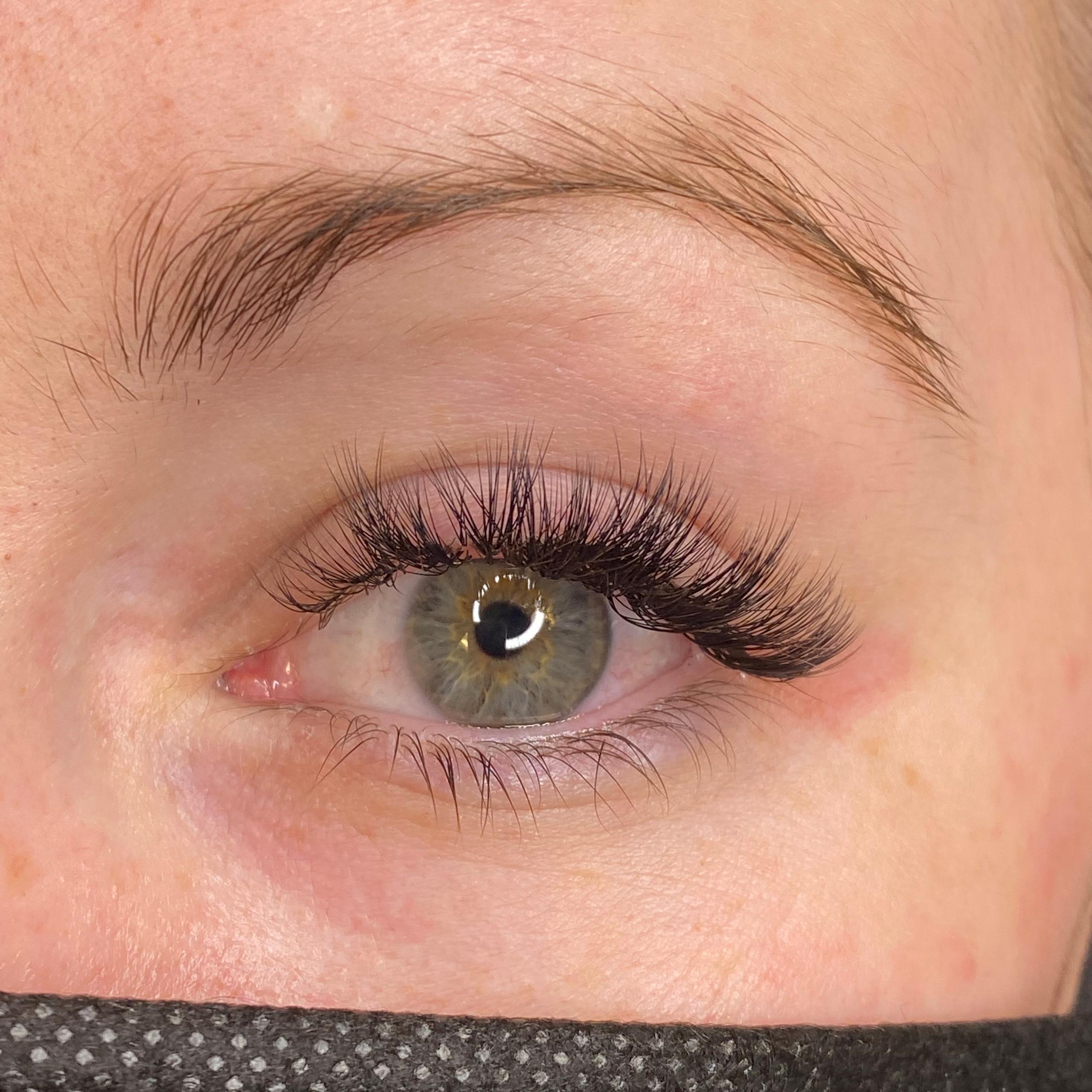 Close-up of a green eye with voluminous dark lash extensions