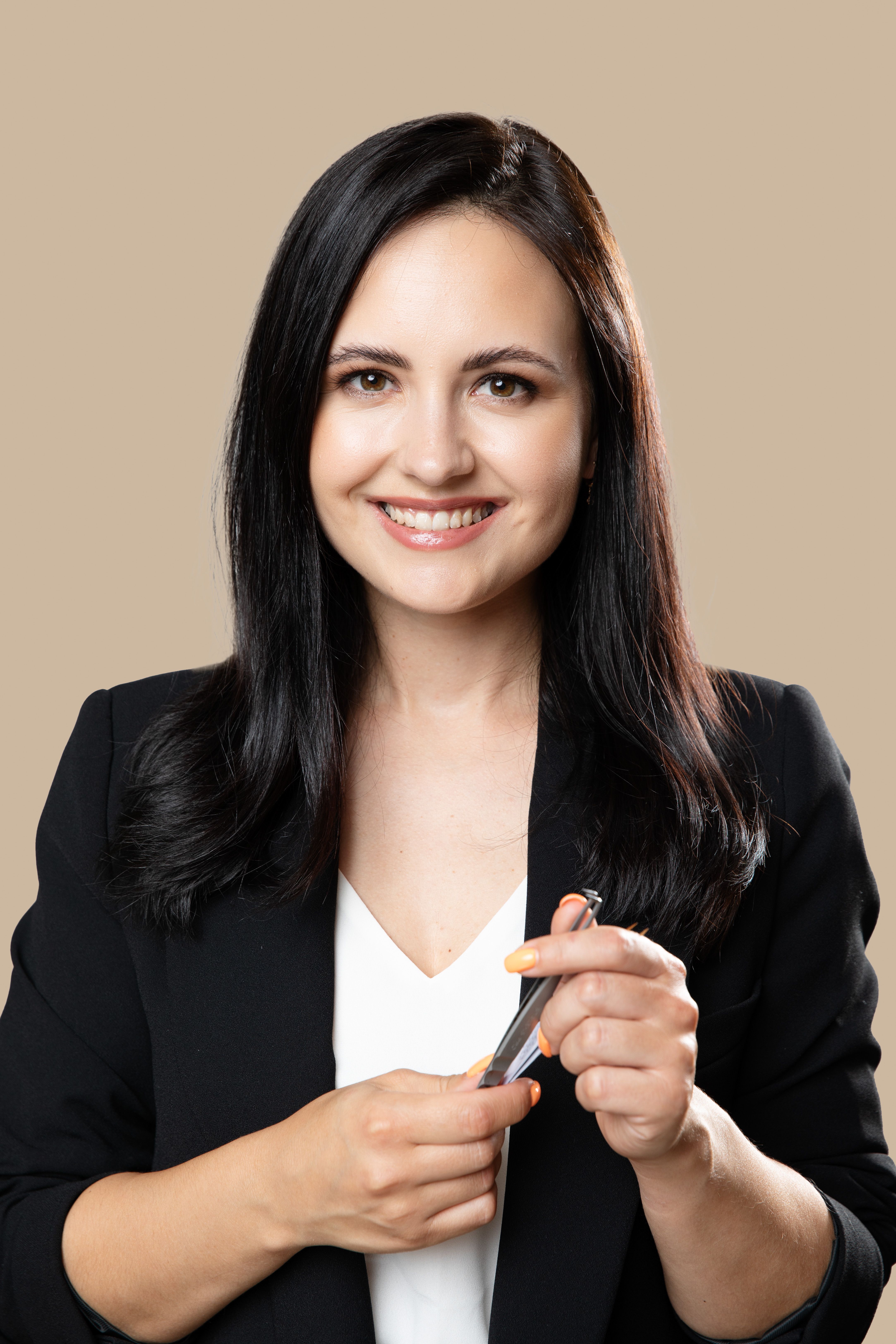 Smiling woman in a black blazer holding tweezers
