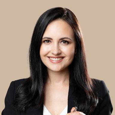 Smiling woman in a black blazer holding tweezers