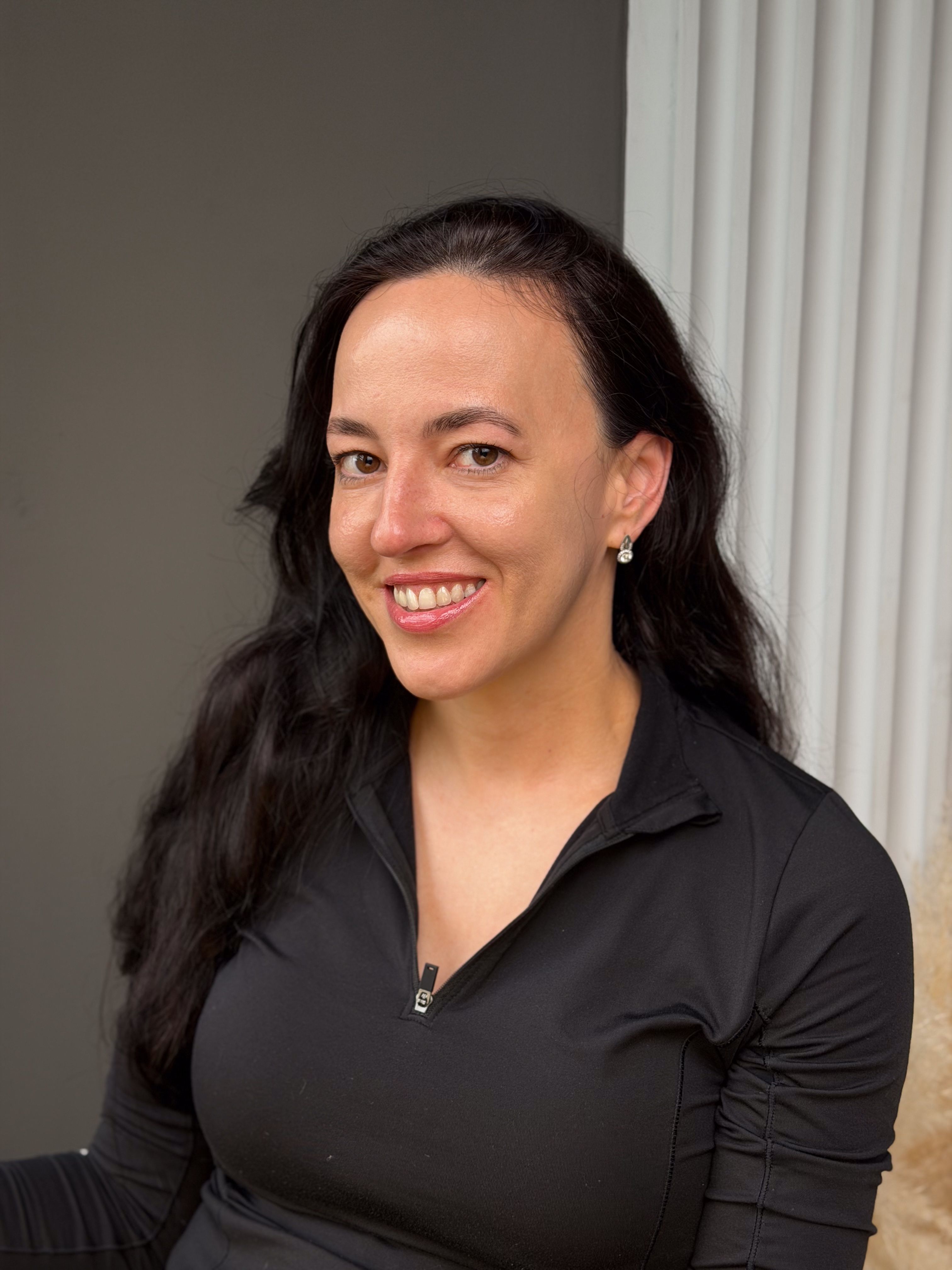 Smiling woman with softly shaped dark eyebrows.
