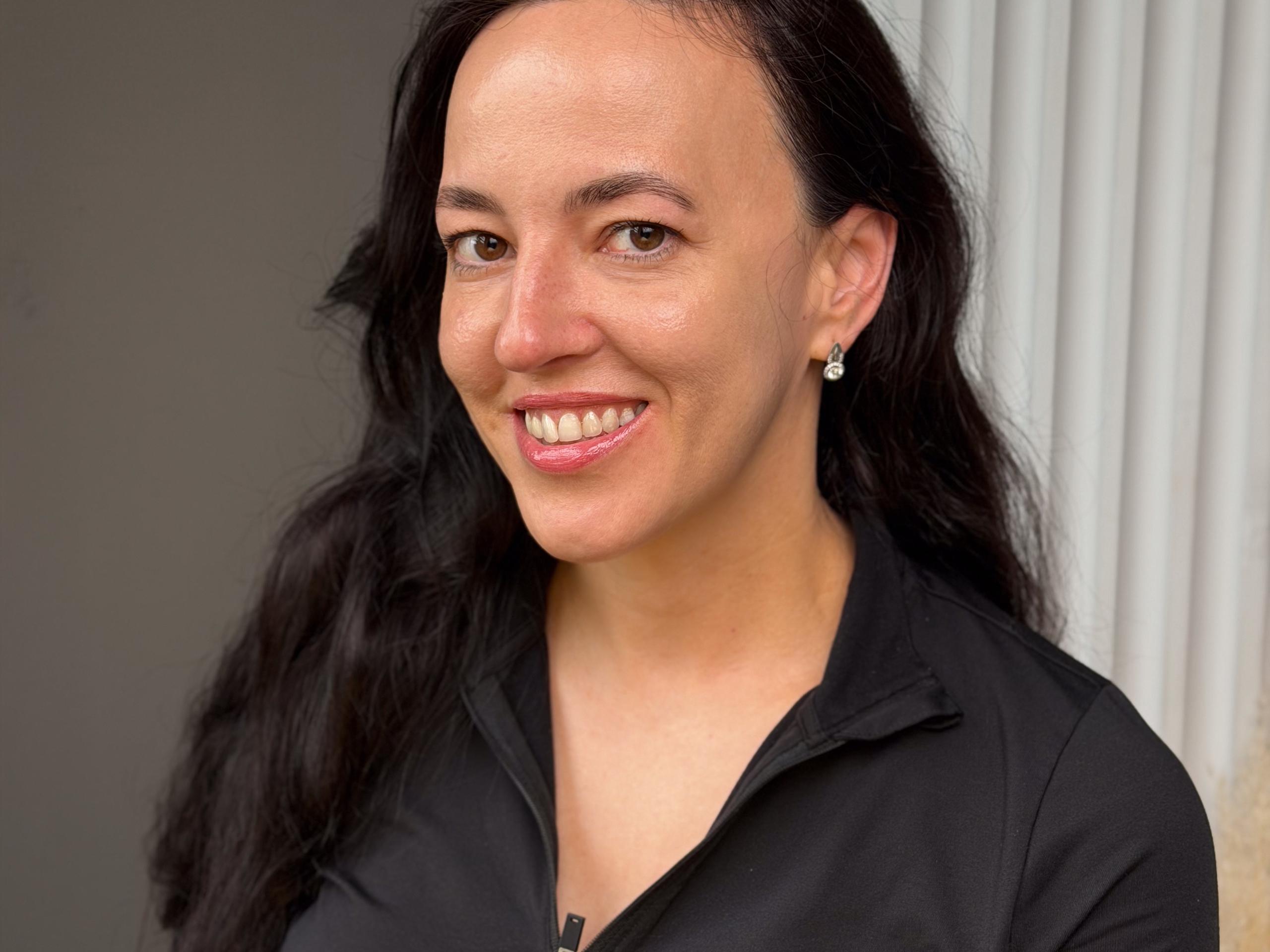 Smiling woman with softly shaped dark eyebrows.