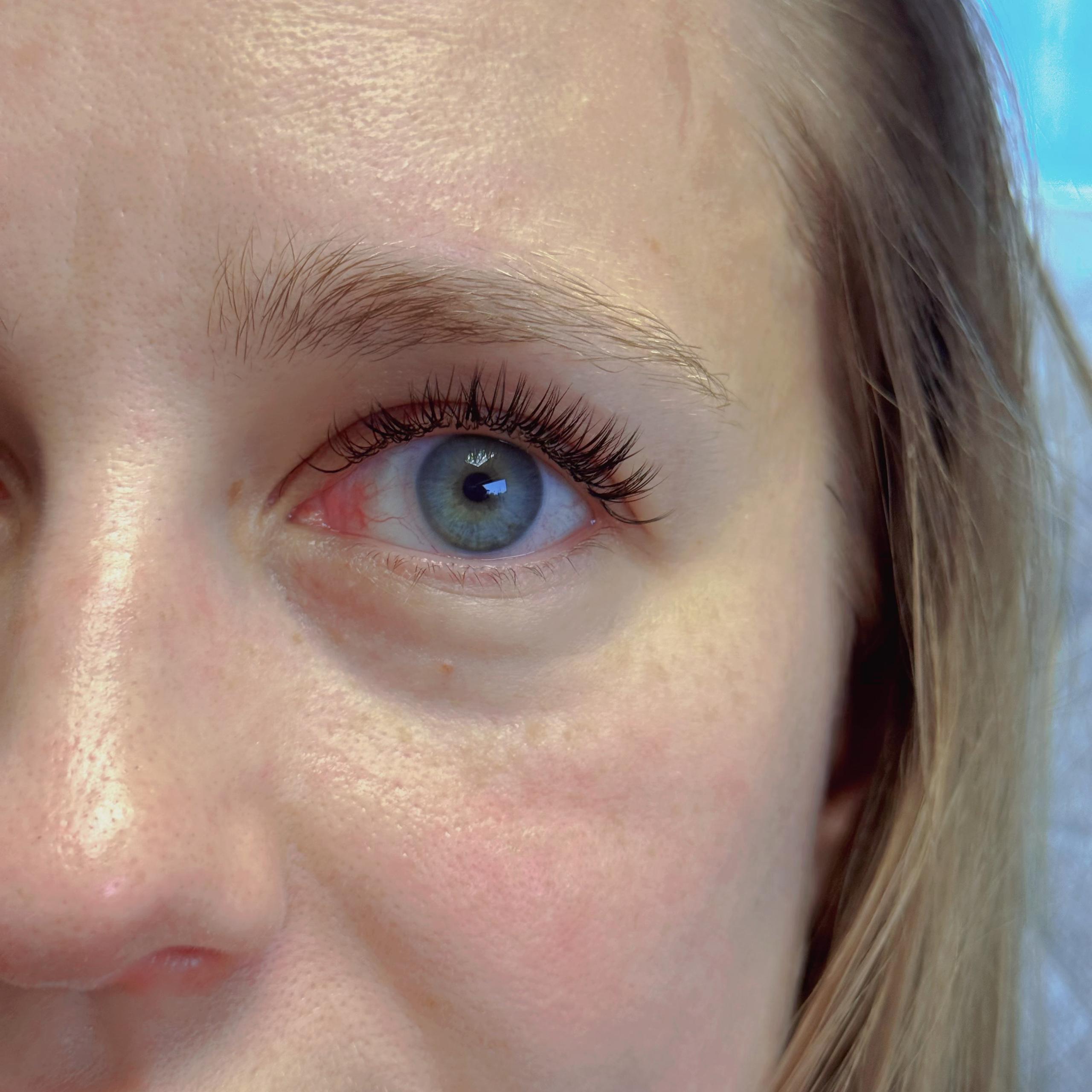 Close-up of a woman's blue eye with dark eyelash extensions
