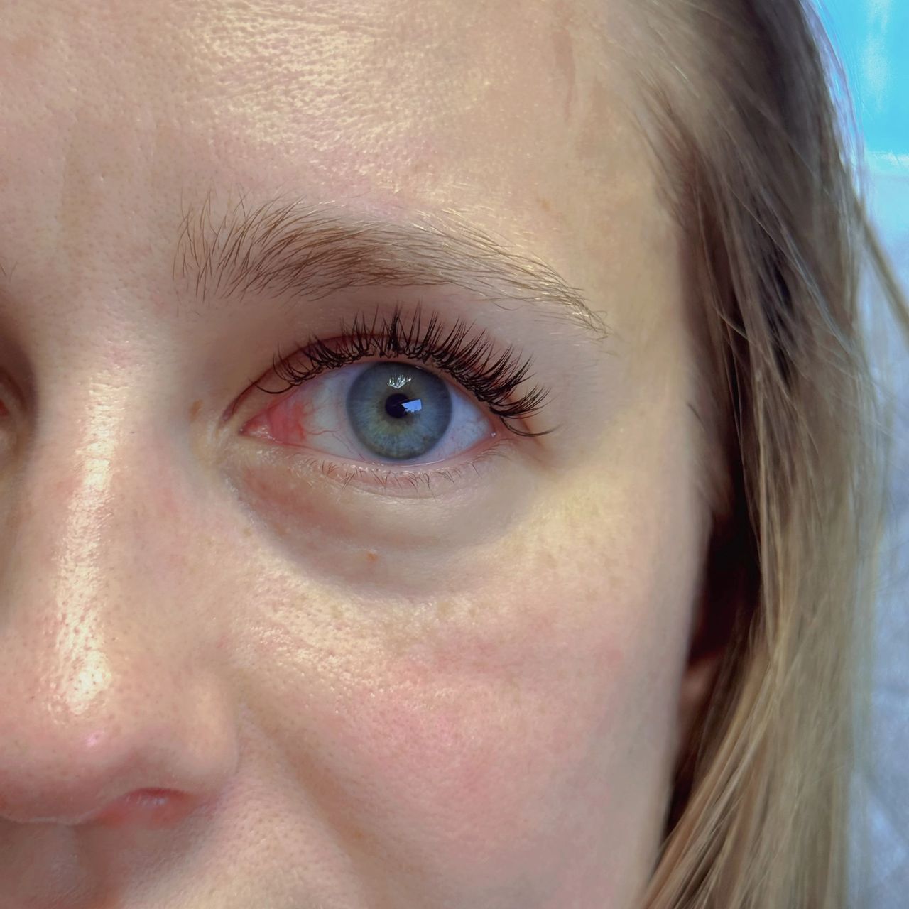 Close-up of a woman's blue eye with dark eyelash extensions