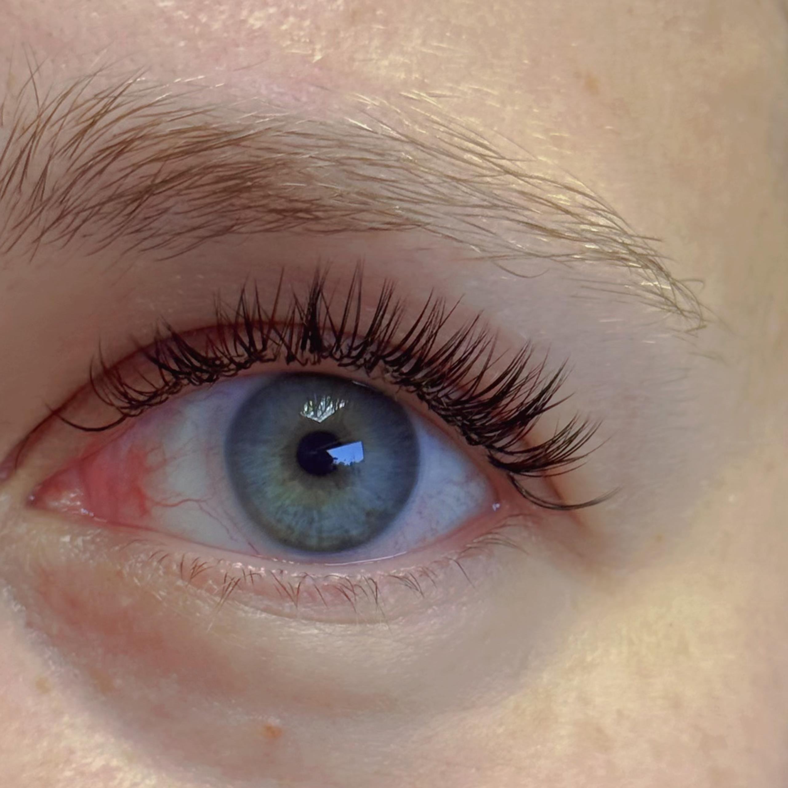 Close-up of a woman's blue eye with dark eyelash extensions