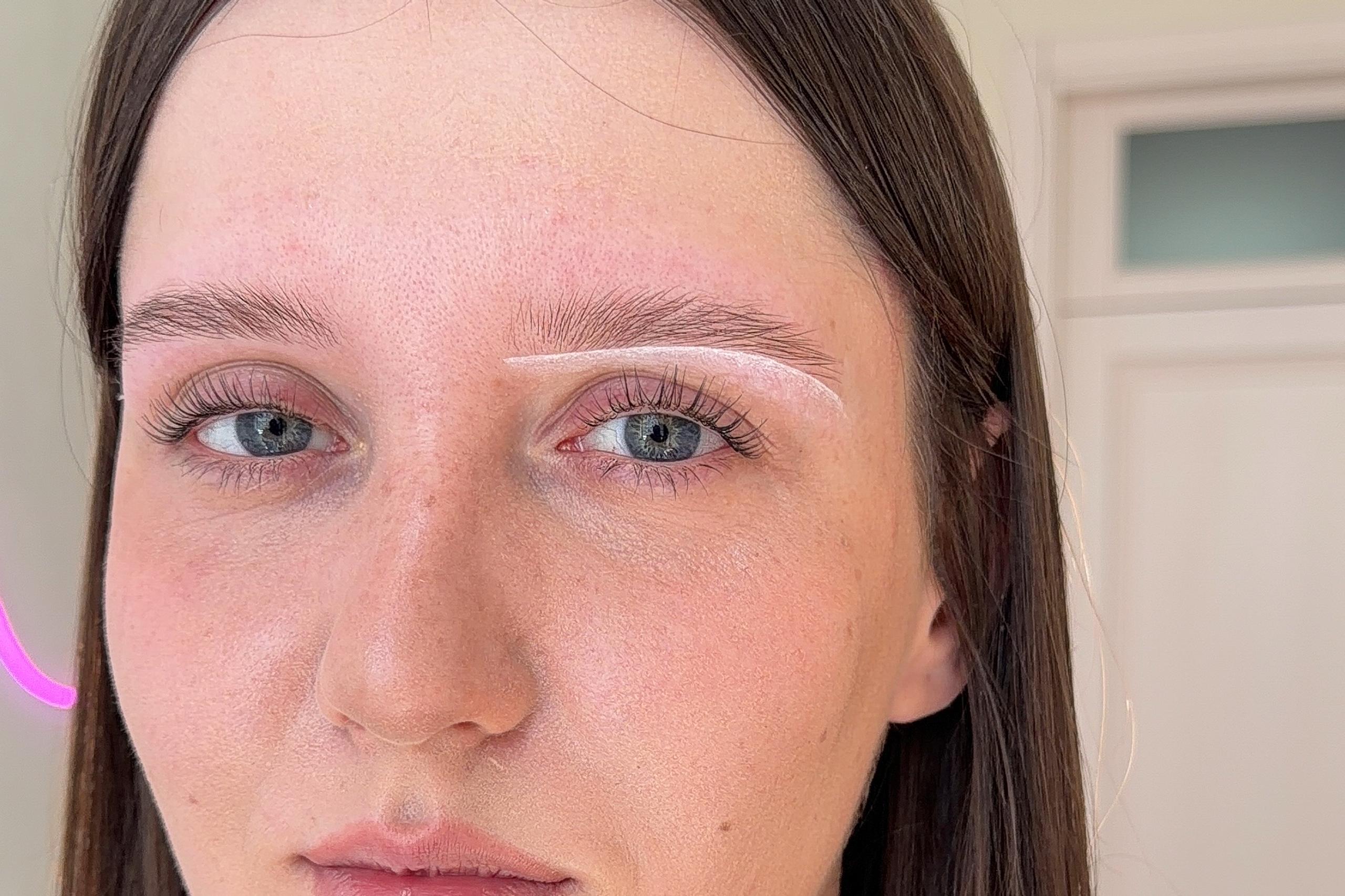 White mapping lines outline the planned shape around a client's eyebrow.