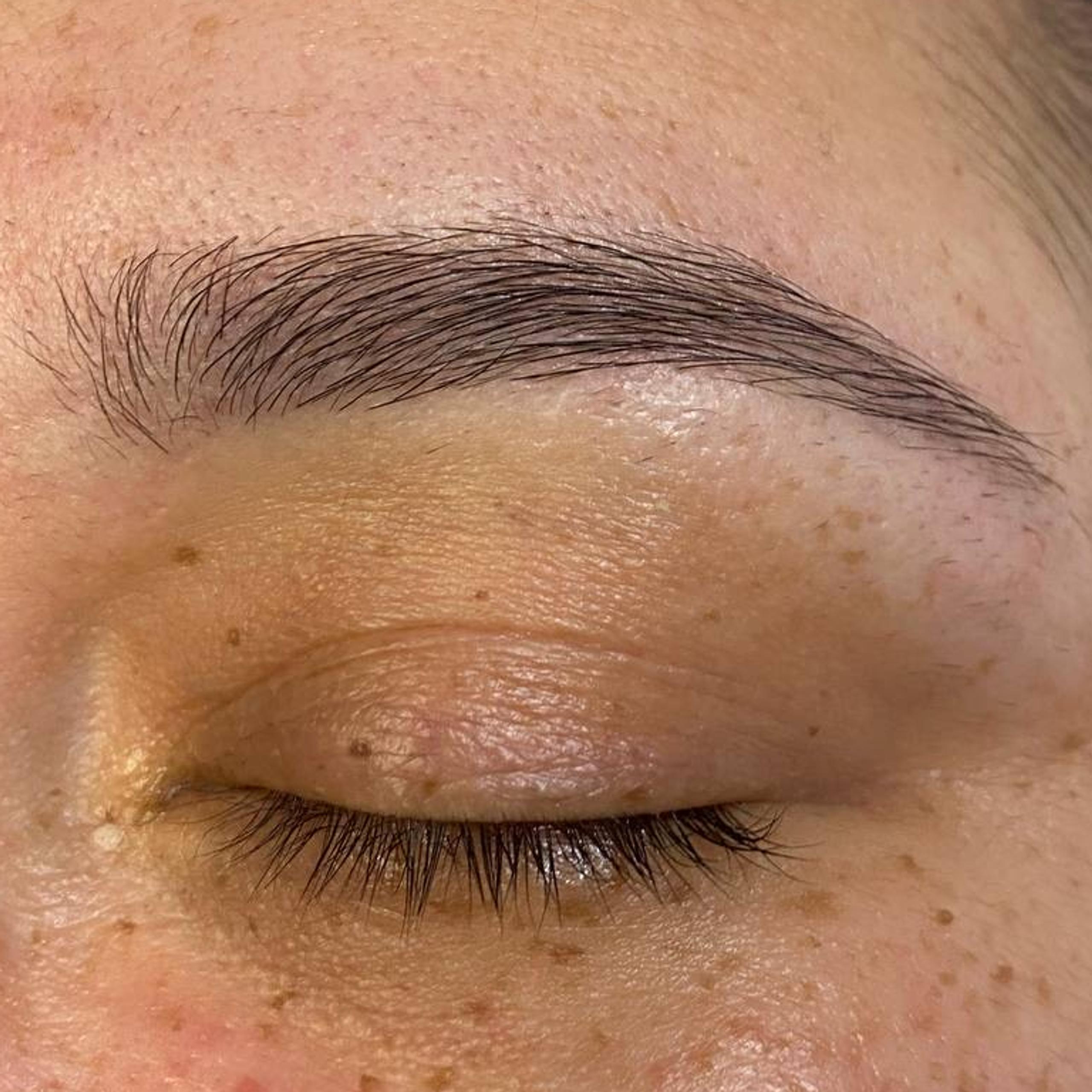 Closed eye with a full dark eyebrow