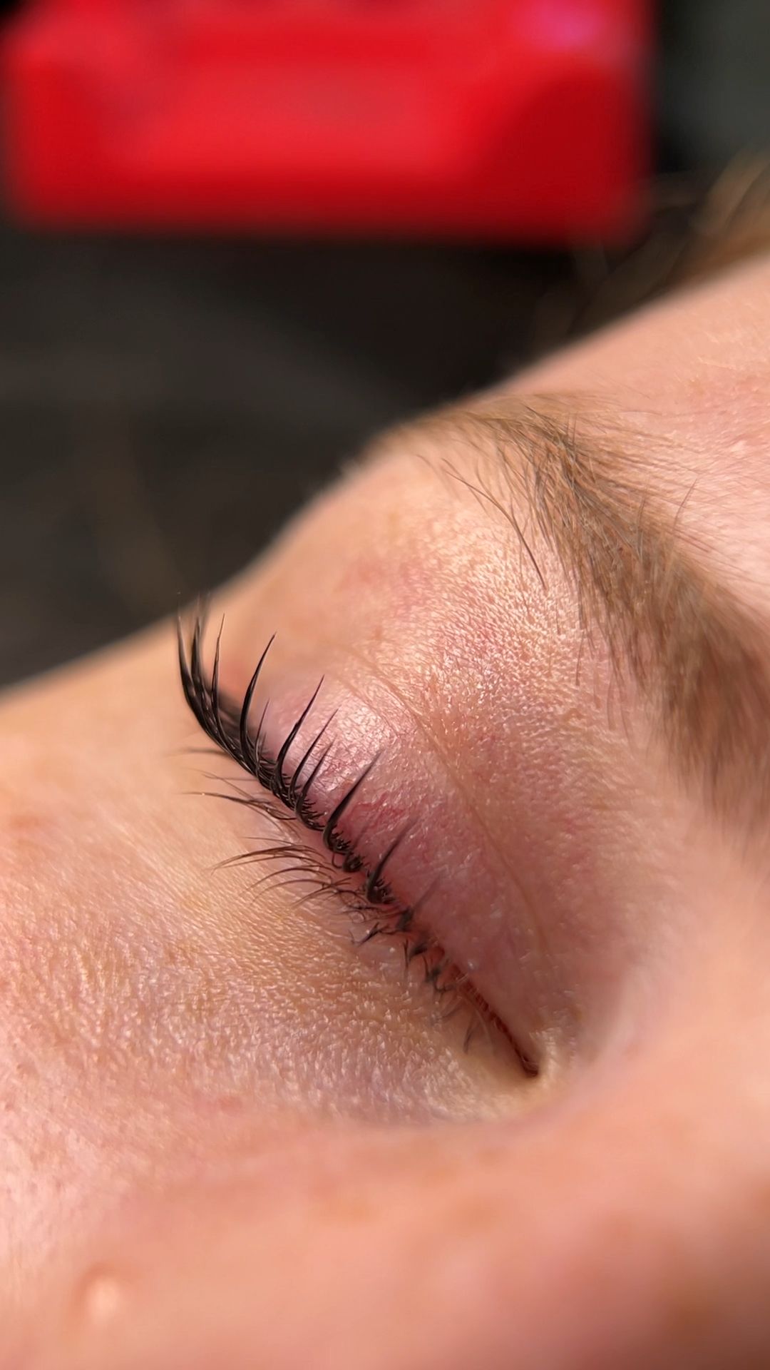 Close-up of finished lash lift result. Eyelashes tinted black, lifted and curled upward from the root.