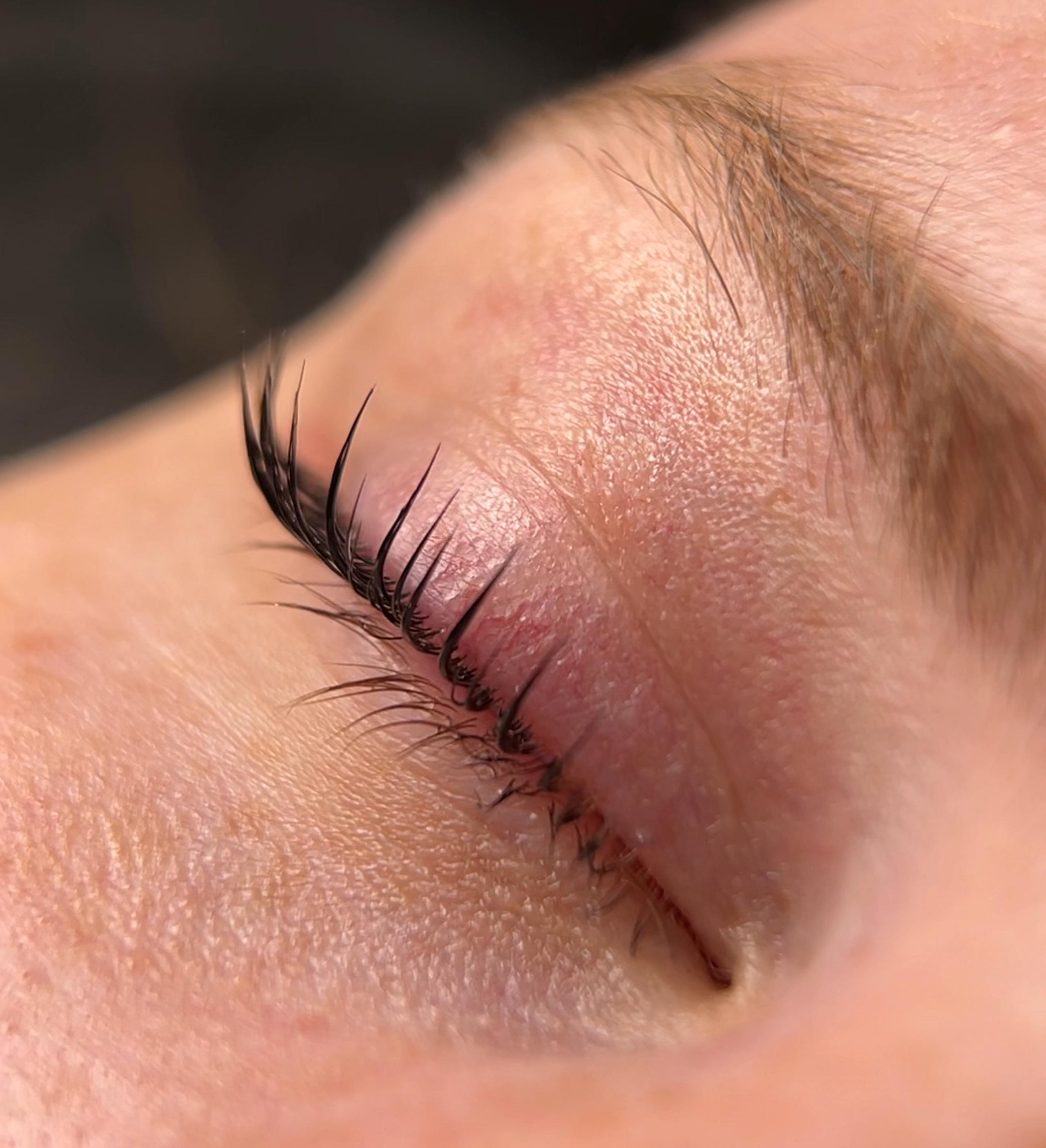 Close-up of finished lash lift result. Eyelashes tinted black, lifted and curled upward from the root.