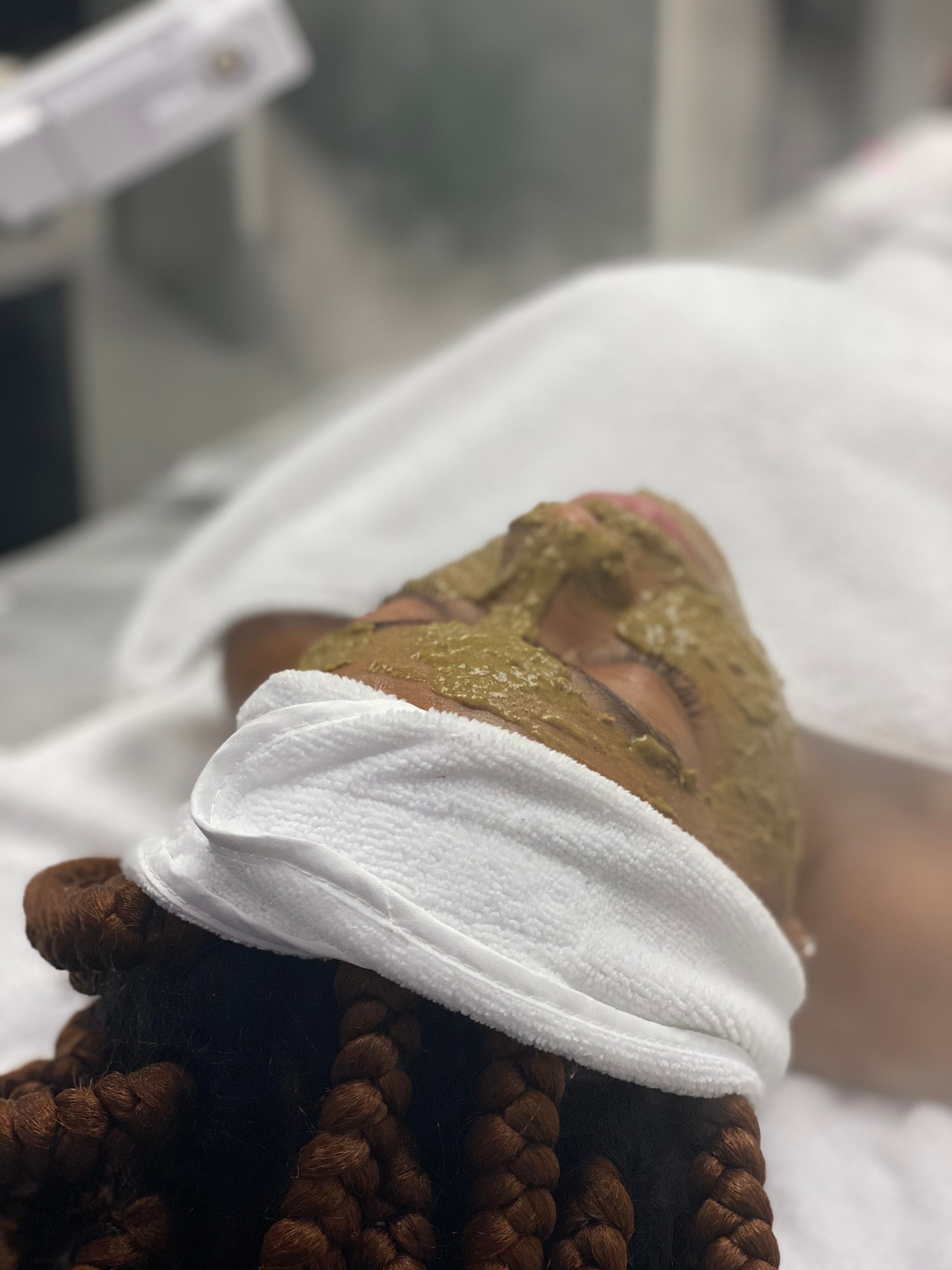 Person with a green face mask and white headband at a spa.