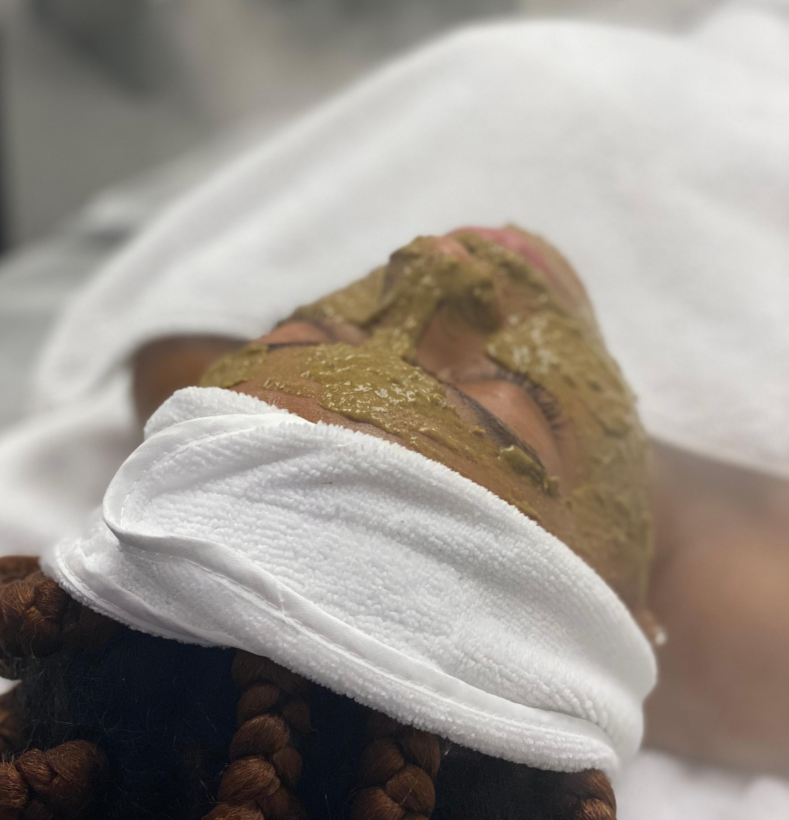 Person with a green face mask and white headband at a spa.