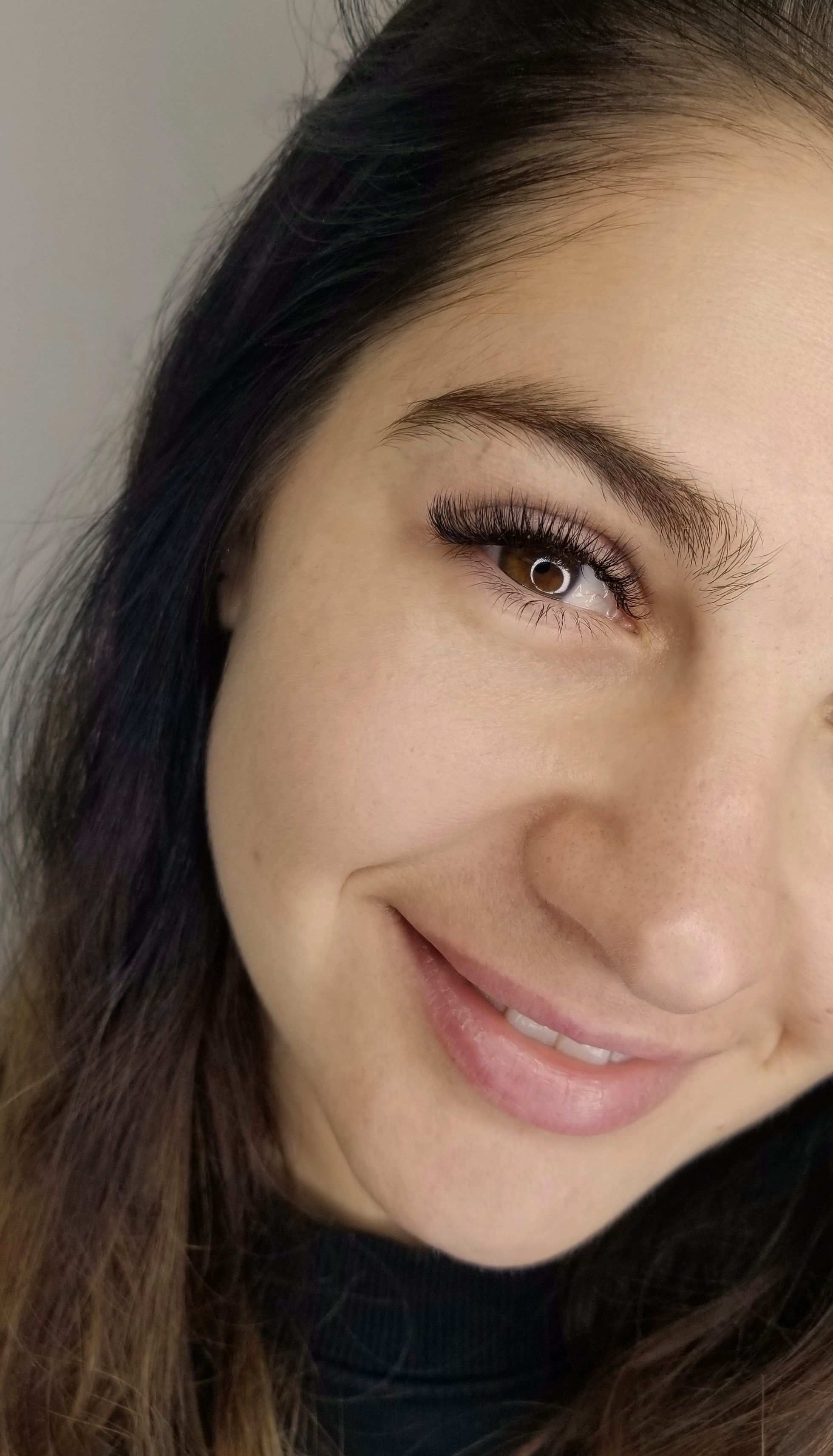 Close-up of a smiling woman's face featuring voluminous lash extensions.