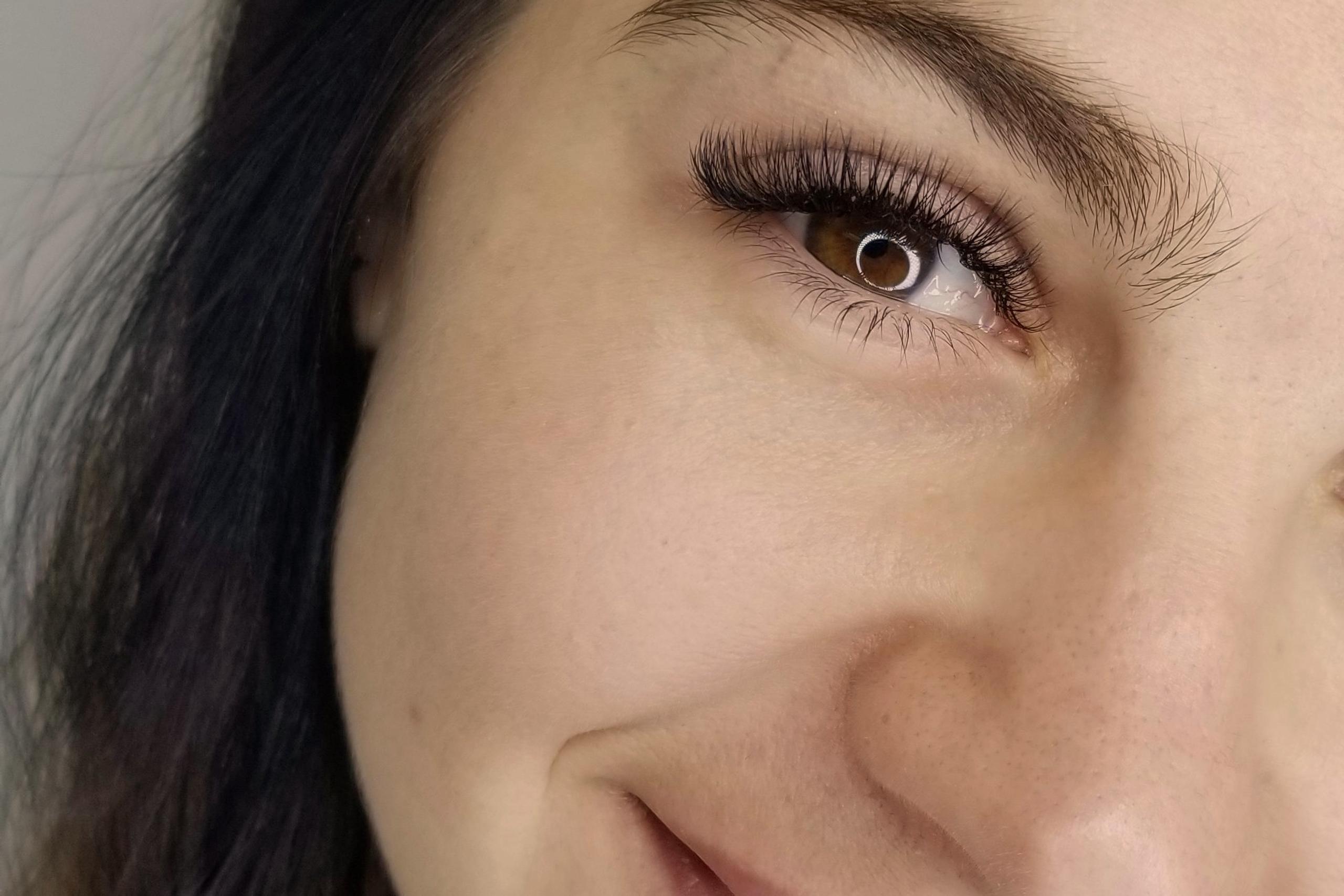 Close-up of a smiling woman's face featuring voluminous lash extensions.