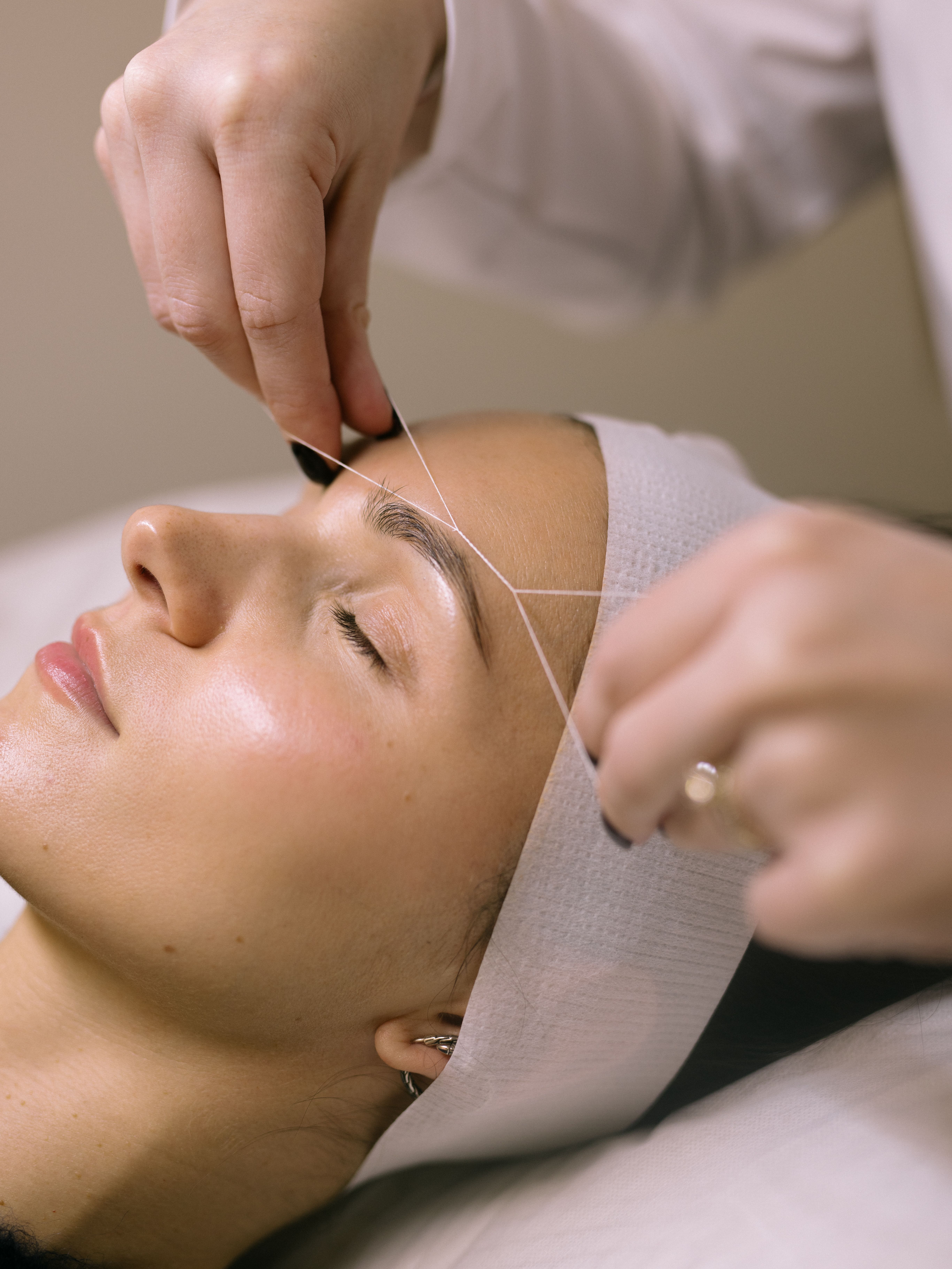 A woman getting her eyebrows threaded.