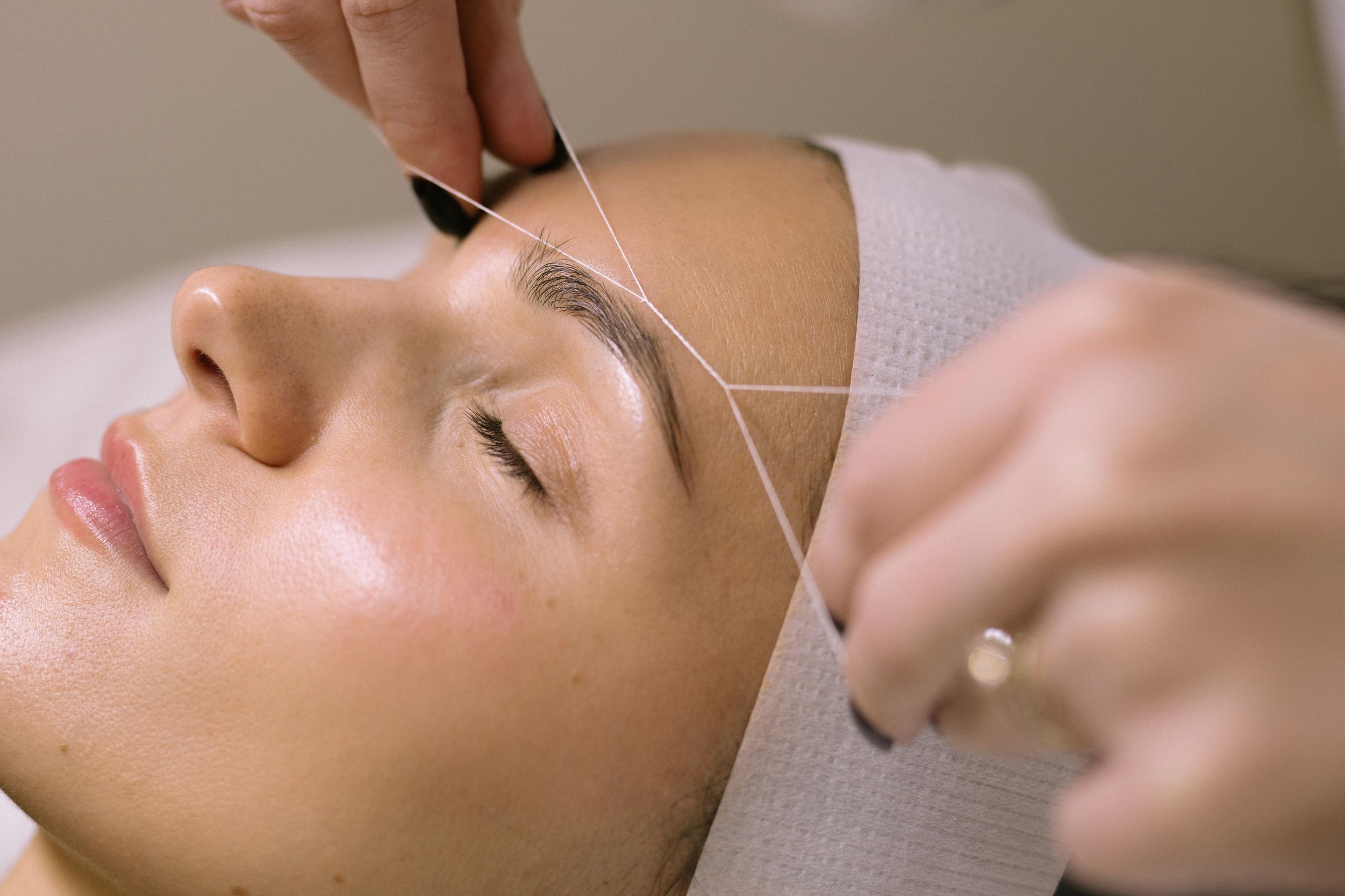 A woman getting her eyebrows threaded.
