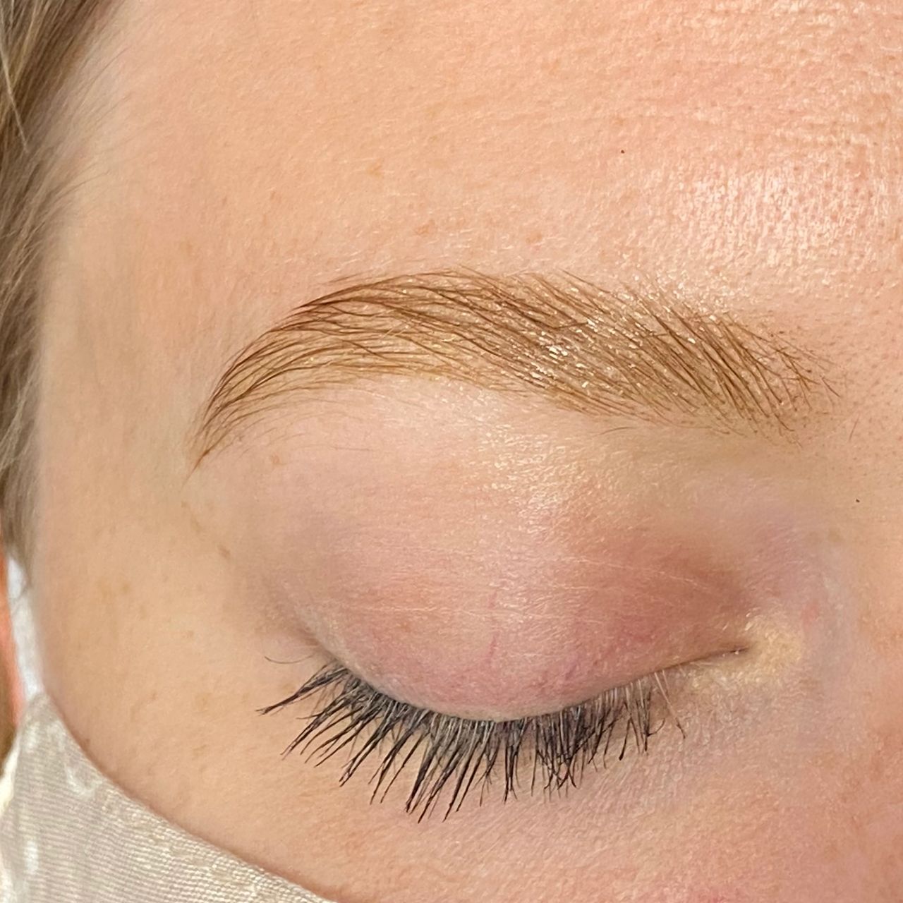 Close-up of a person's face with closed eyes, well-groomed eyebrows