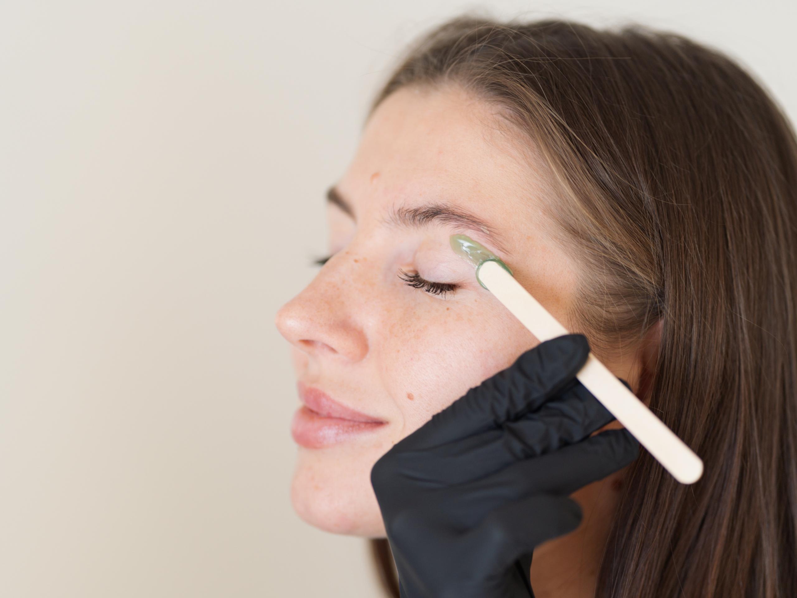 A woman getting her eyebrow waxed.