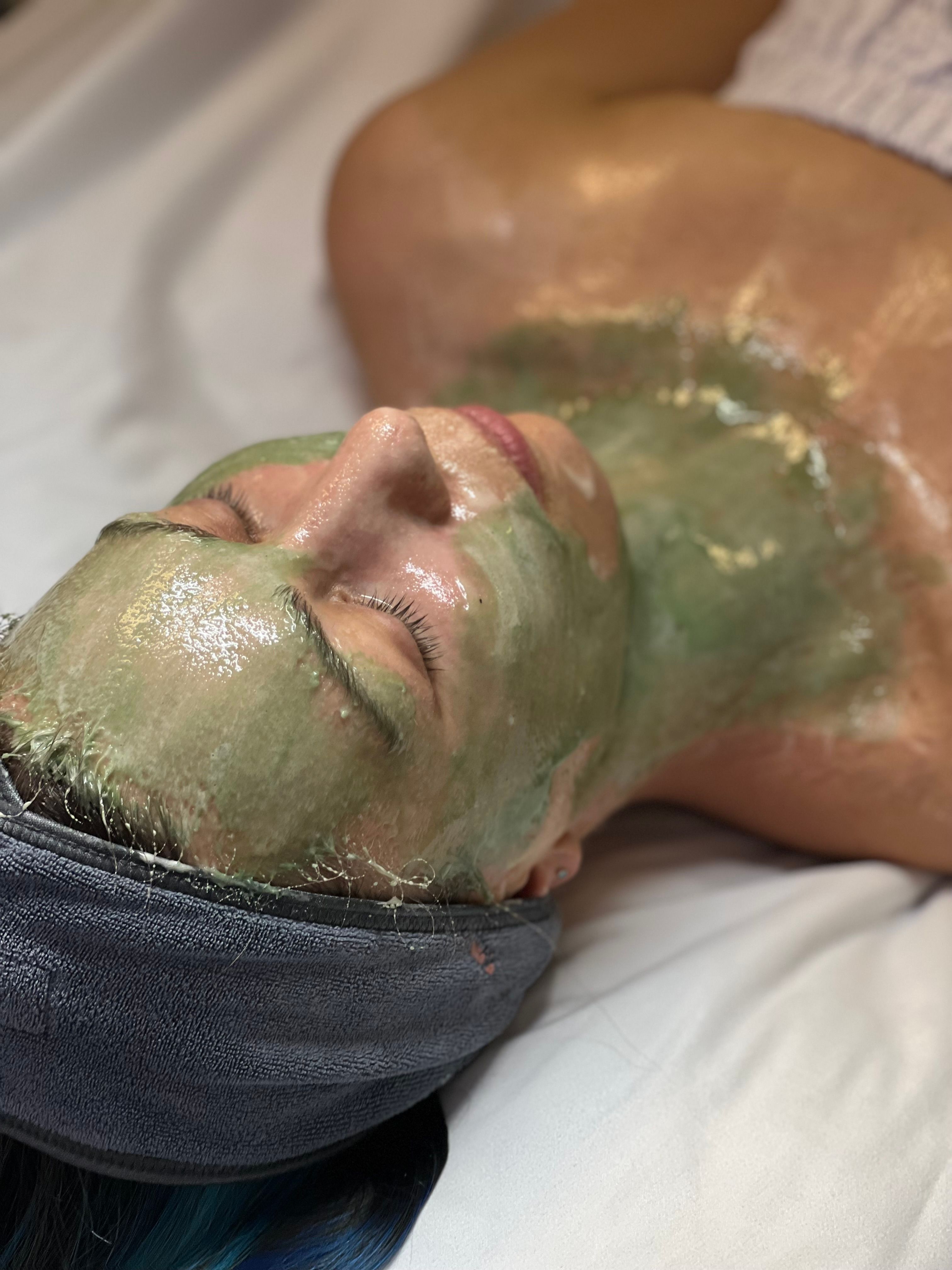 Person lying down with a green face and chest mask.