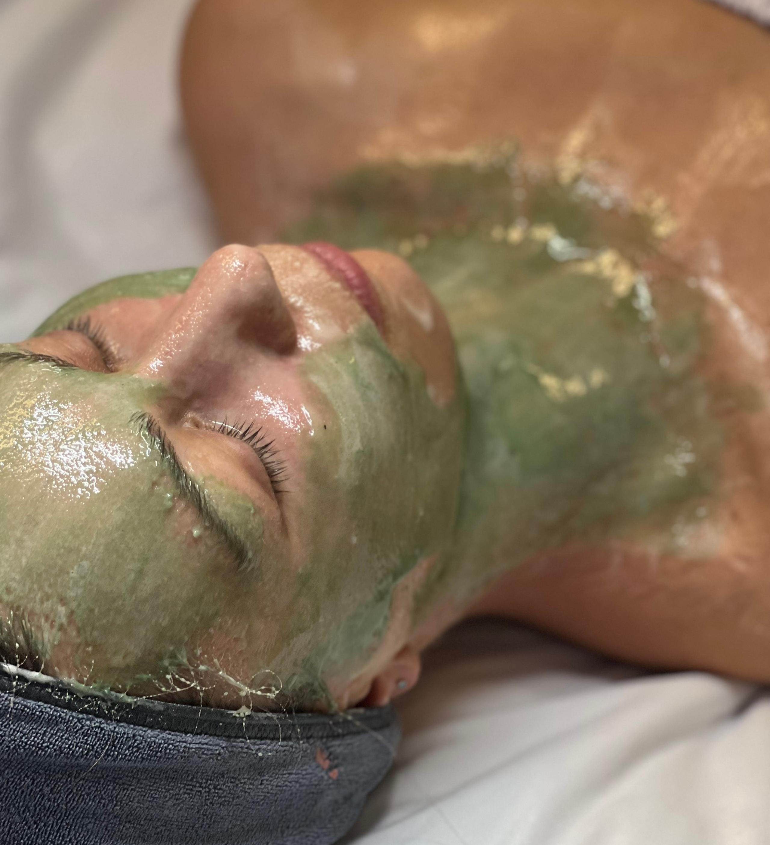 Person lying down with a green face and chest mask.
