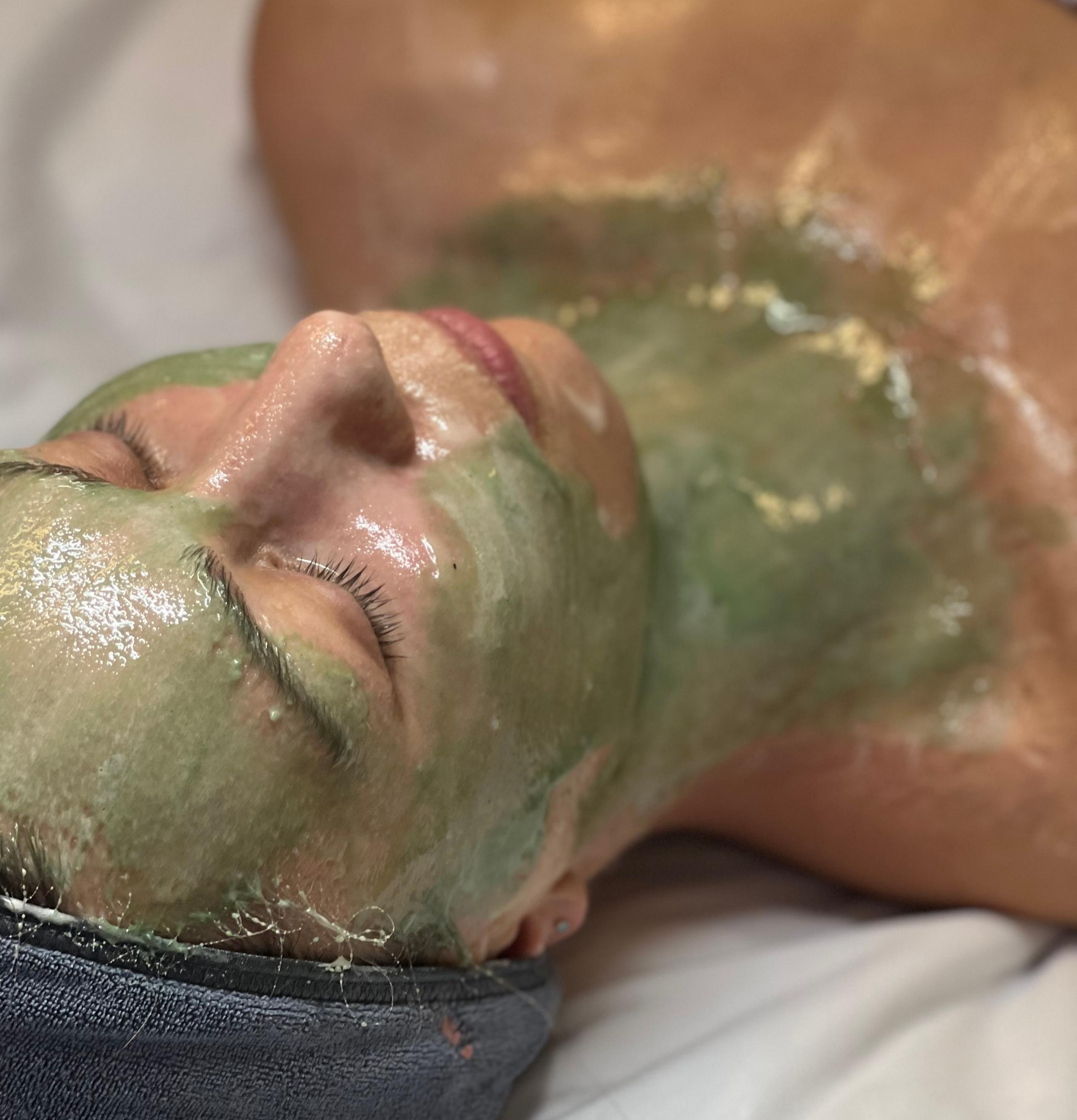 Person lying down with a green face and chest mask.