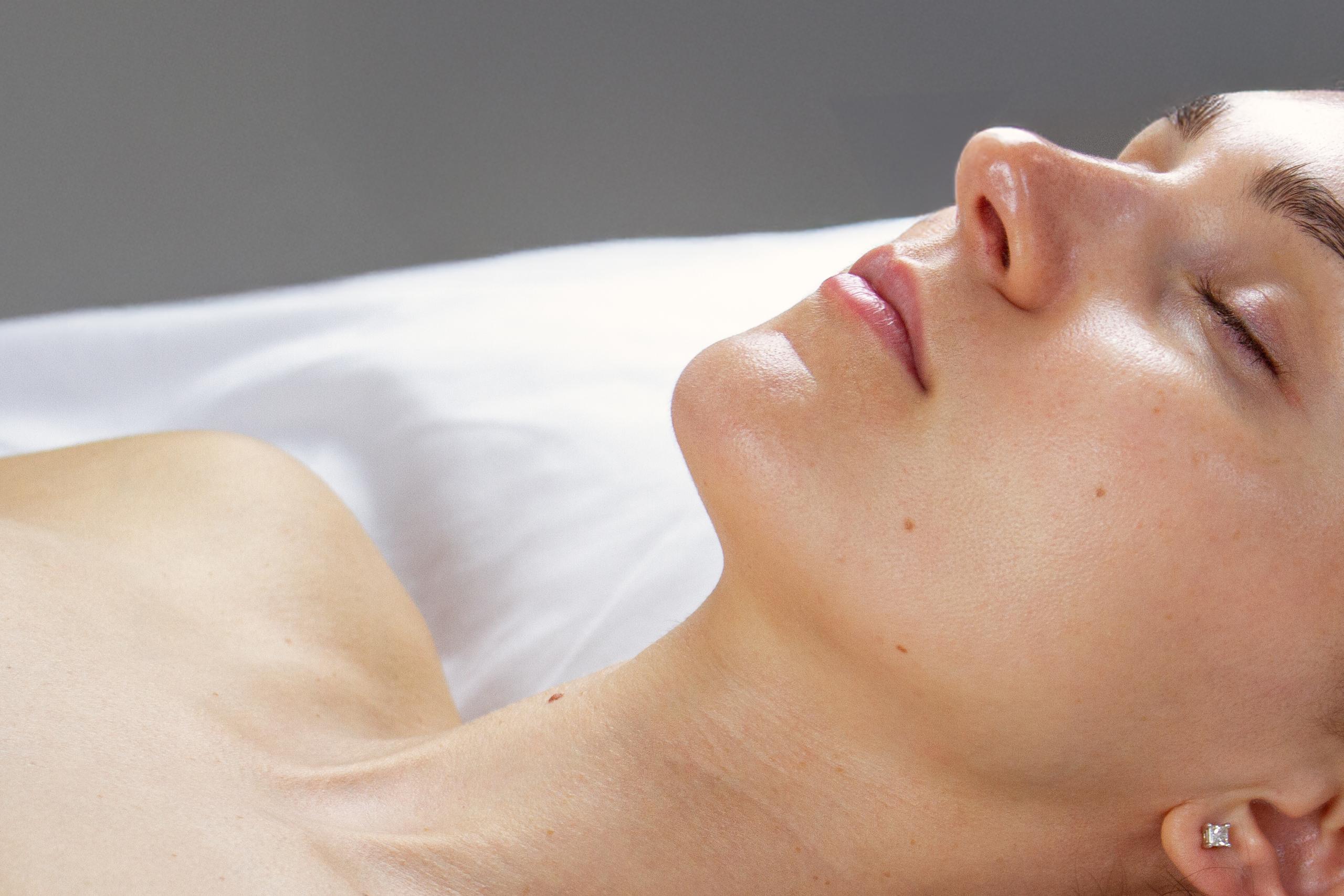 Close-up side profile of a person's jawline, neck, and upper chest.