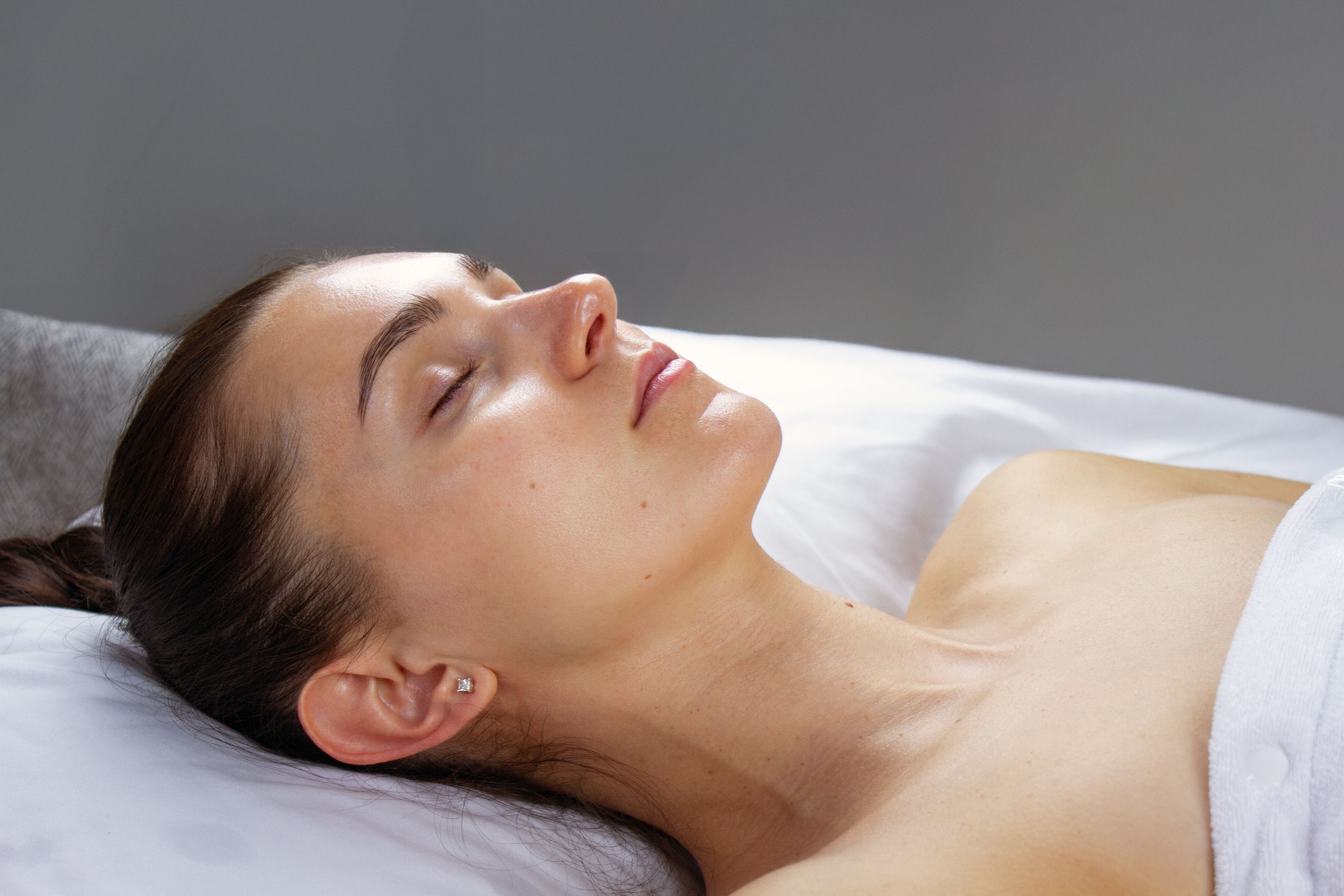 Woman with closed eyes relaxing on a white spa bed.
