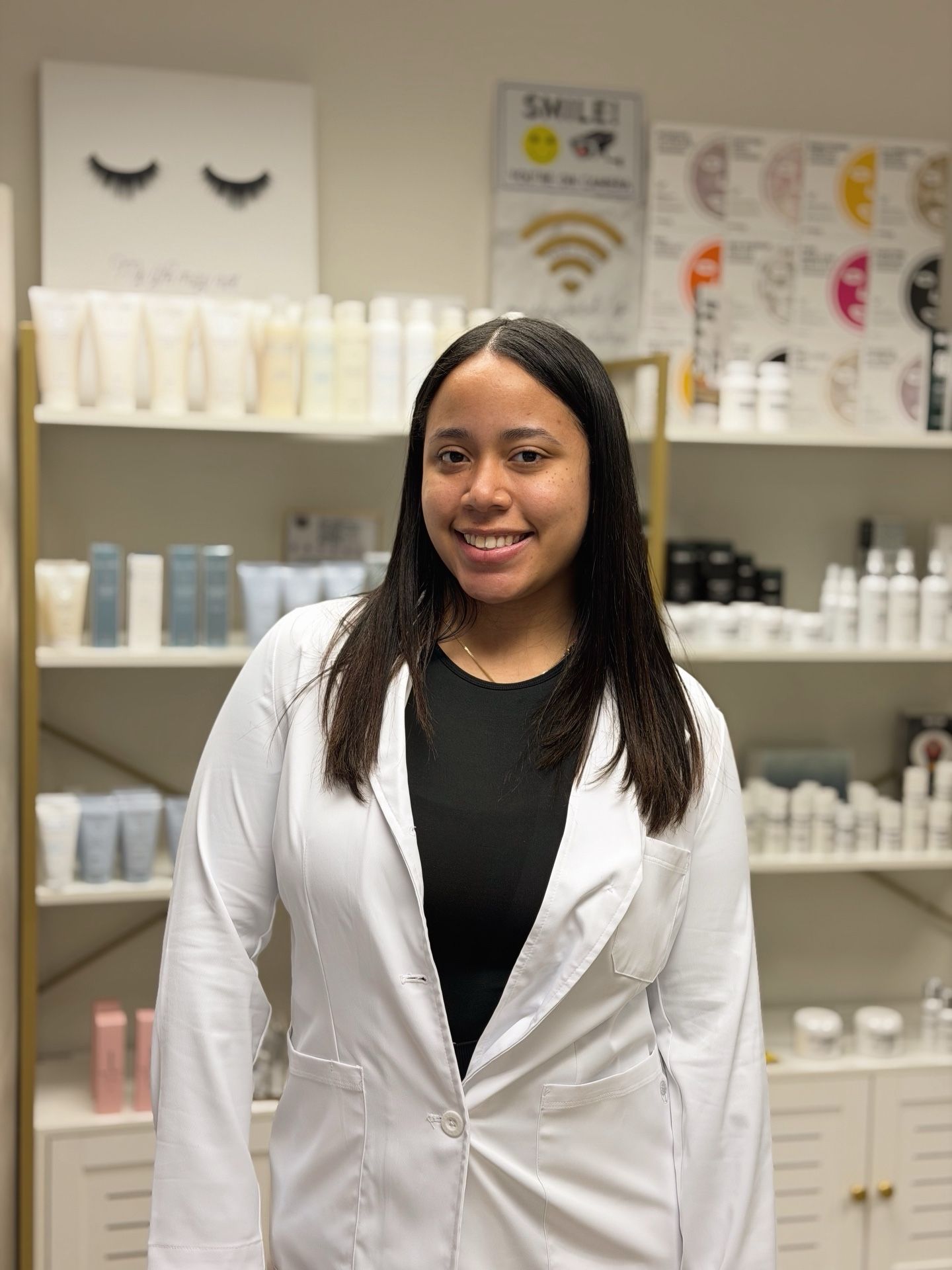 A portrait of a smiling woman in a lab coat in a spa setting