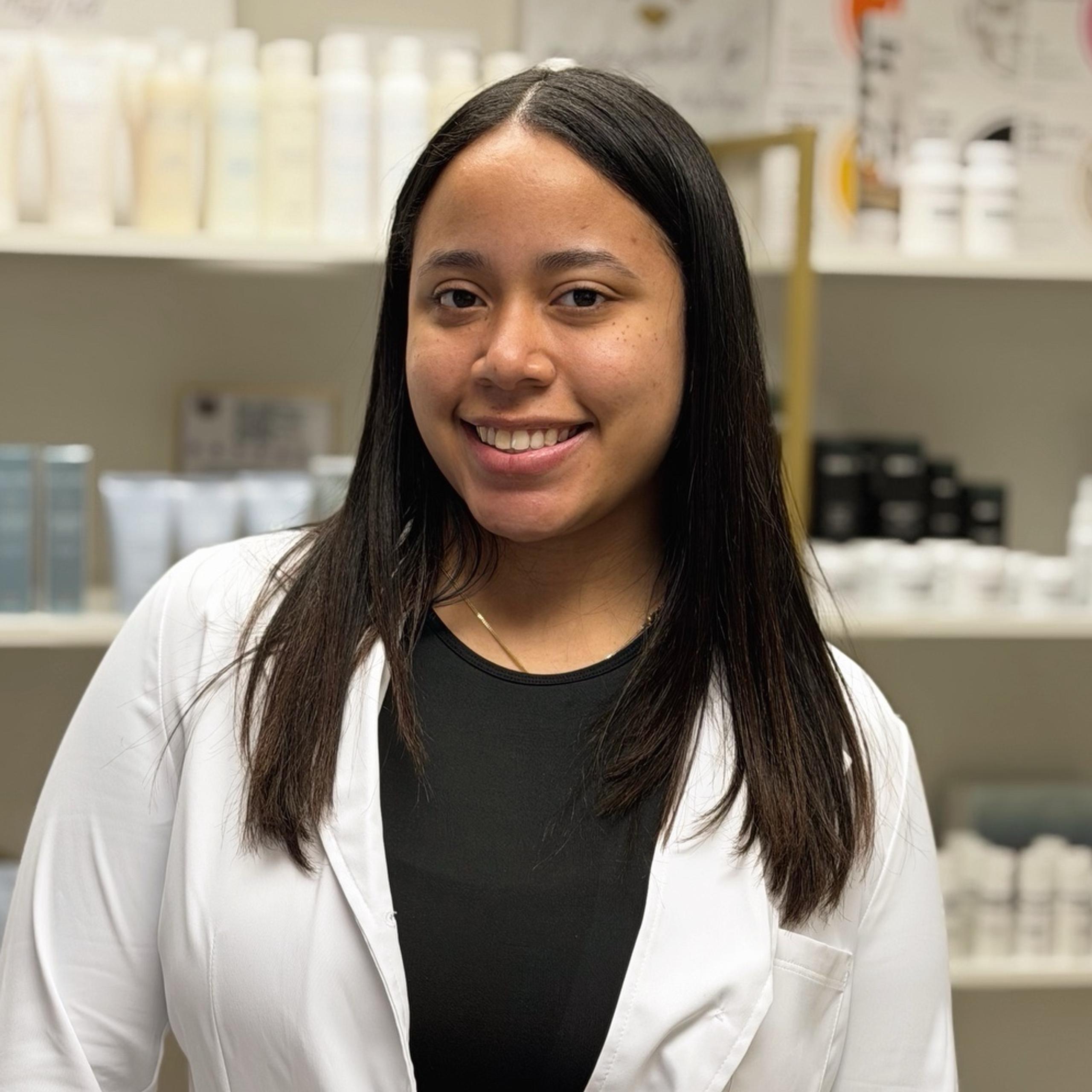 A portrait of a smiling woman in a lab coat in a spa setting