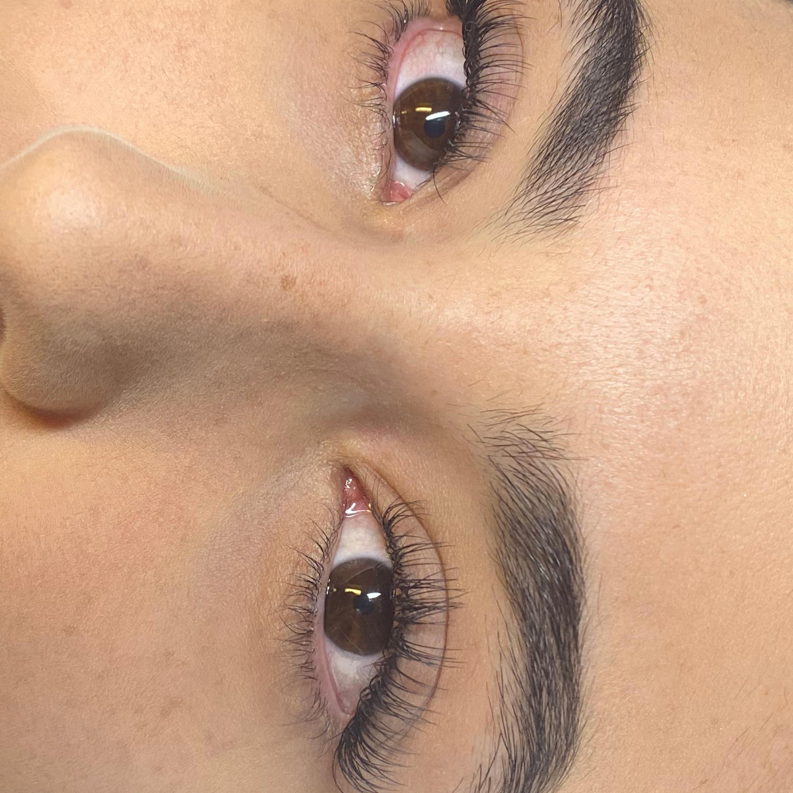 Close-up of a woman lying down with dark brows, long lashes, and pink lipstick.
