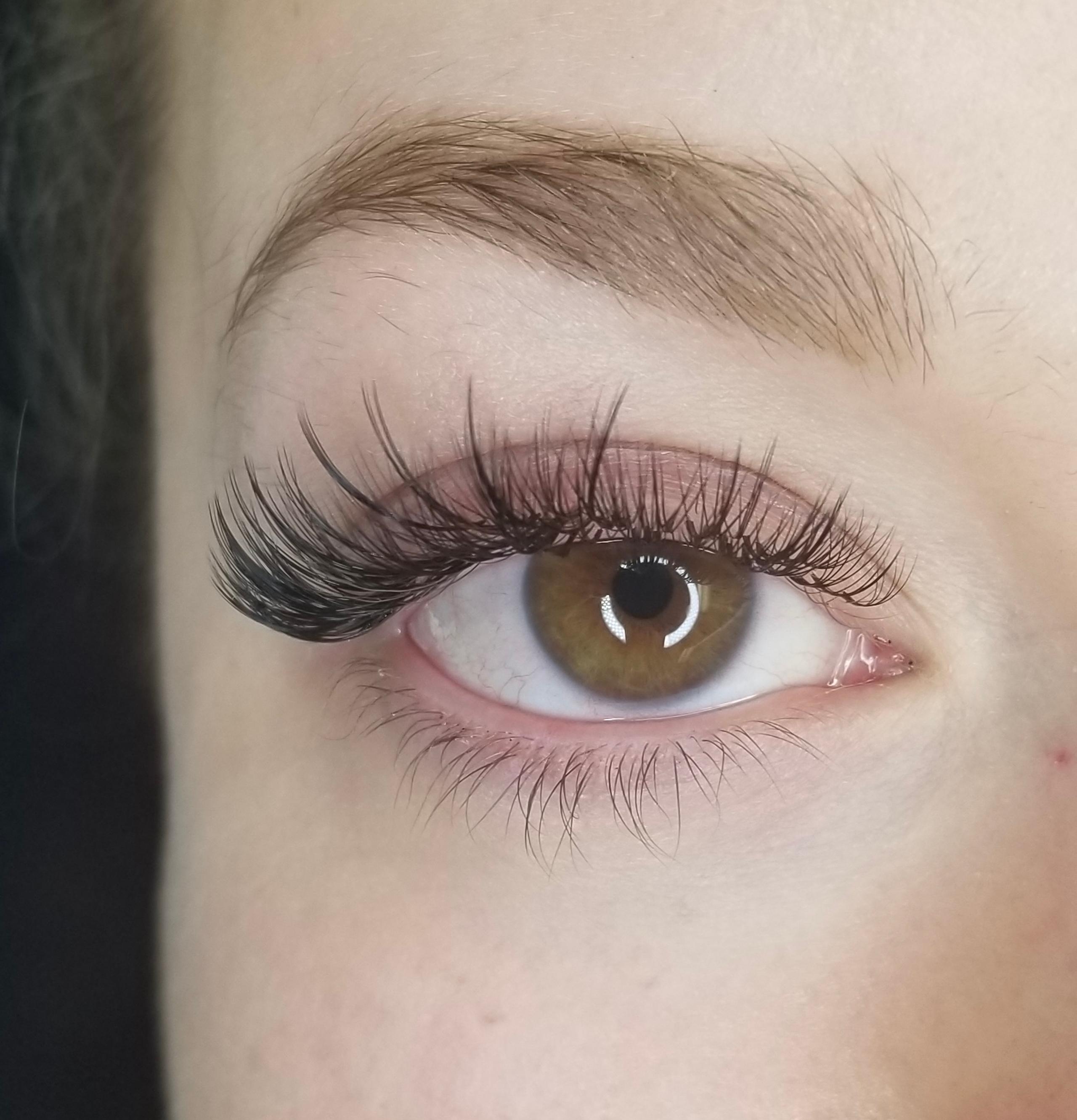 Close-up of a brown eye with long, dark false eyelashes.