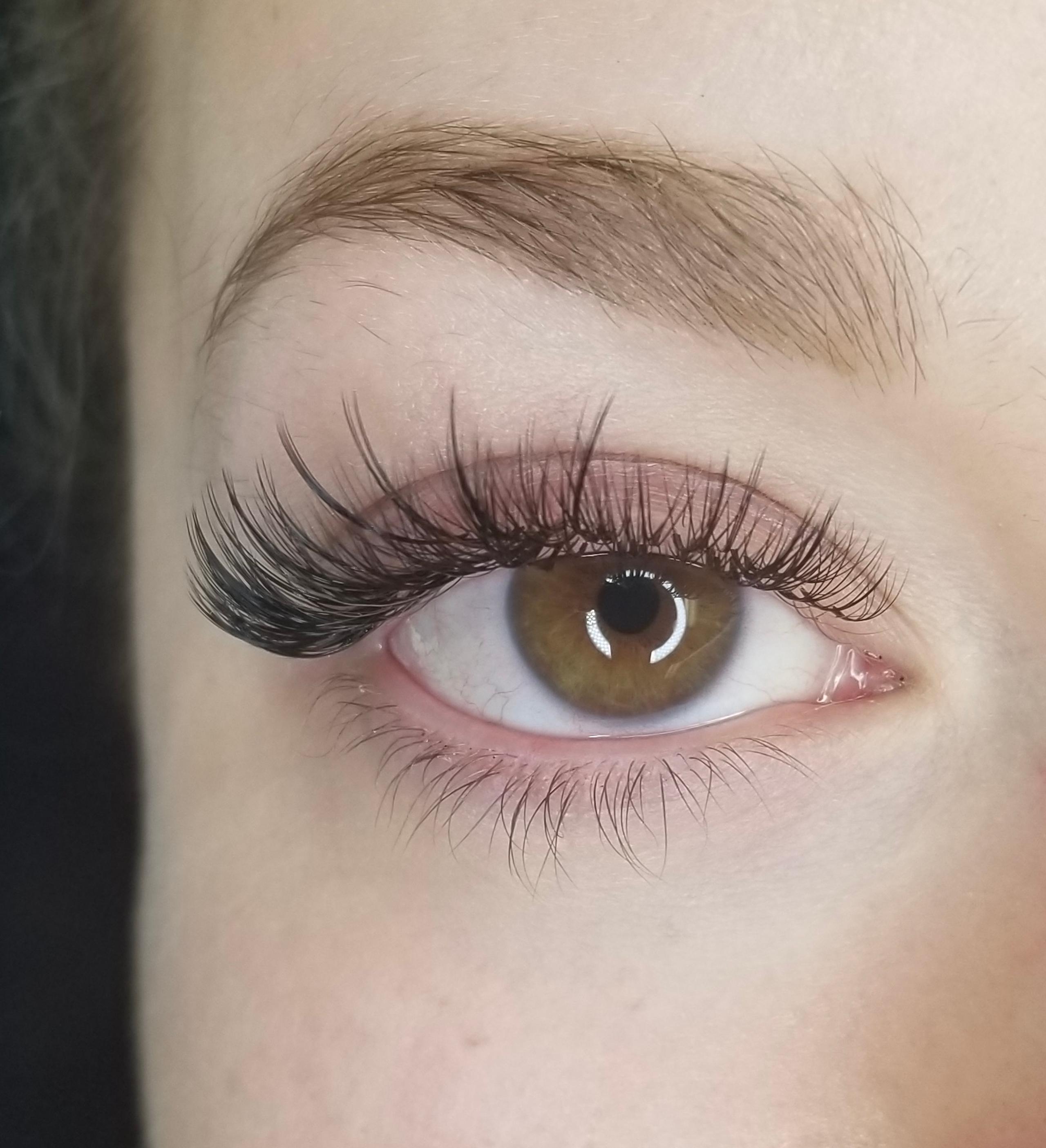 Close-up of a brown eye with long, dark false eyelashes.