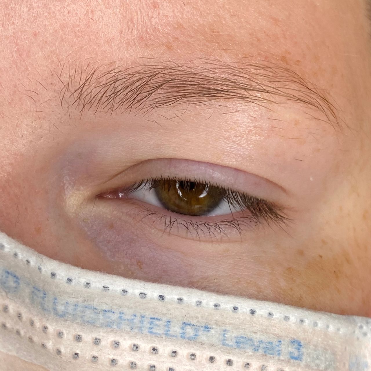 Close-up of a person's brown eye and light colored eyebrow