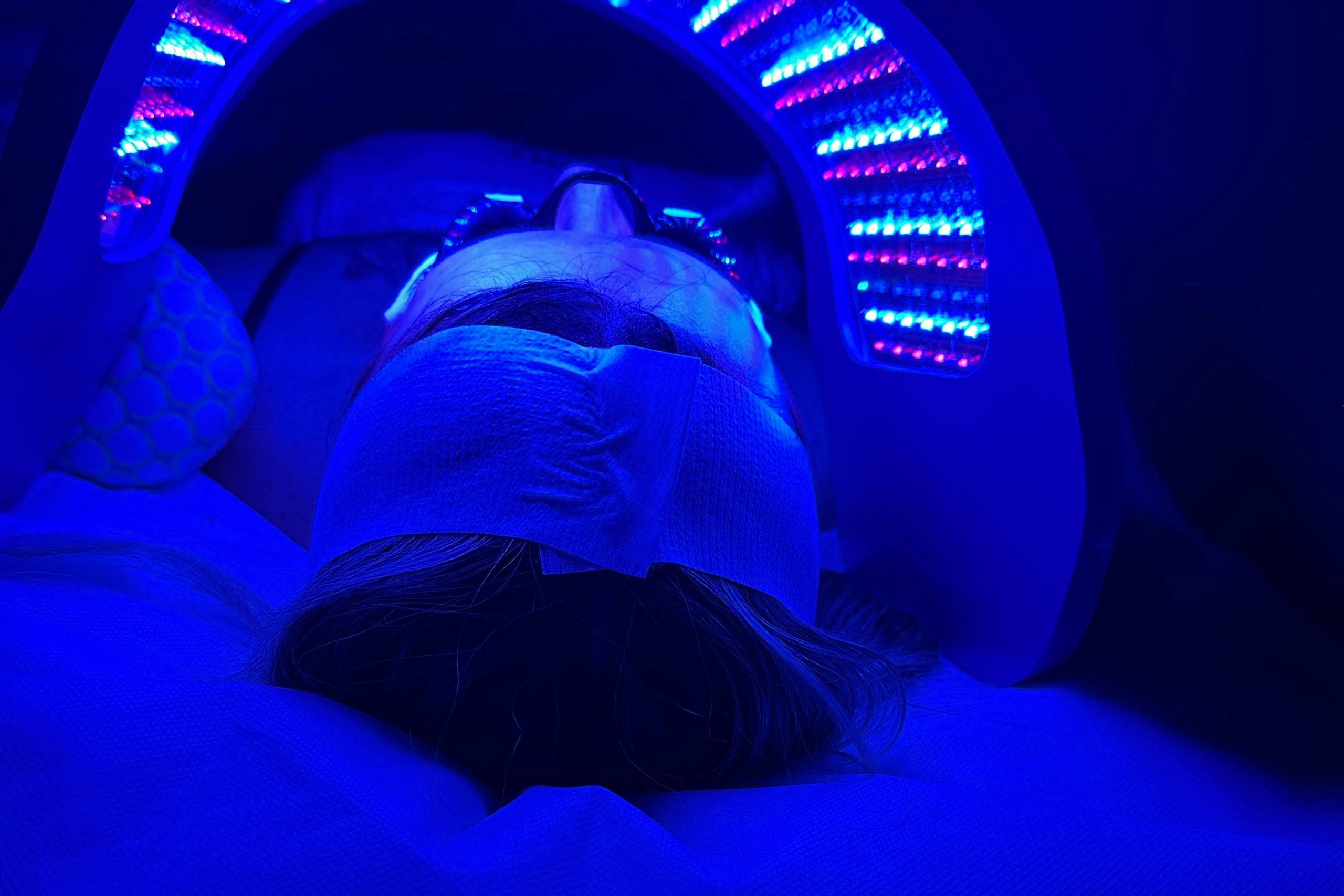 Person receiving LED light therapy with blue and pink lights.