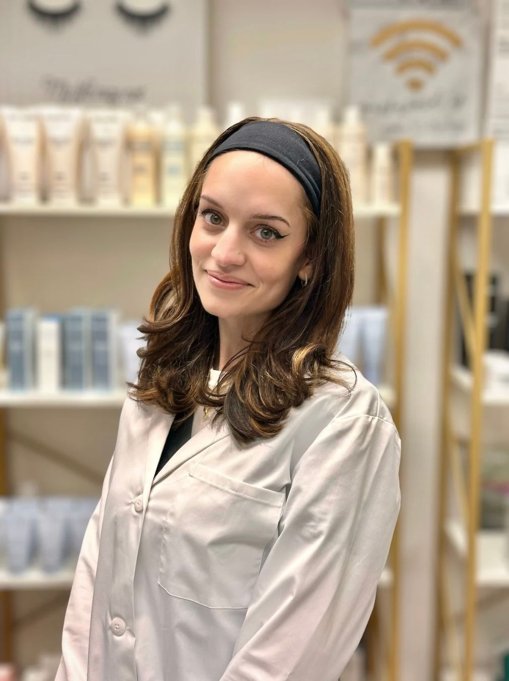 Portrait of a smiling woman with brown hair and a black headband in a spa setting