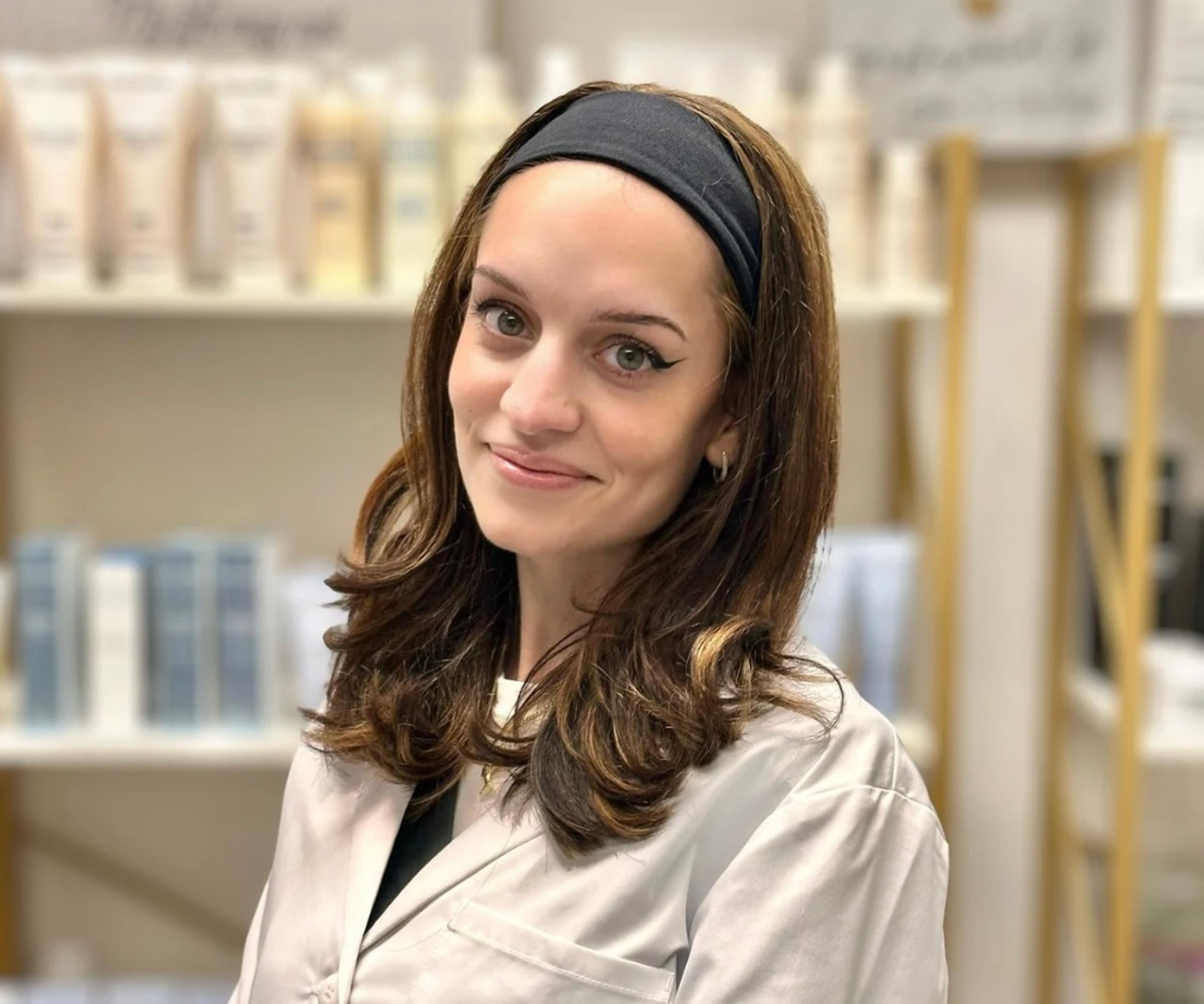 Portrait of a smiling woman with brown hair and a black headband in a spa setting