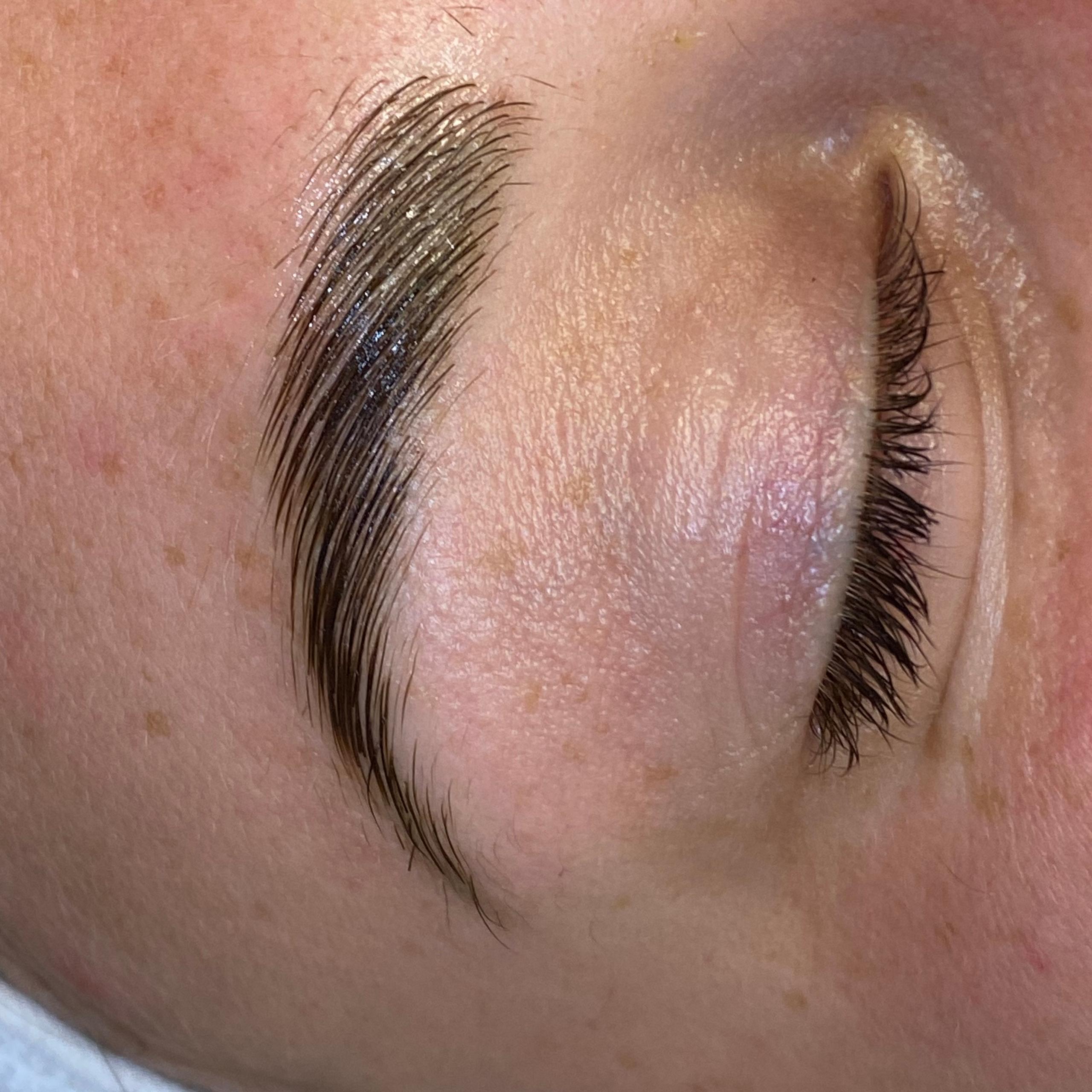 Close-up of a person's laminated eyebrow and closed eye.
