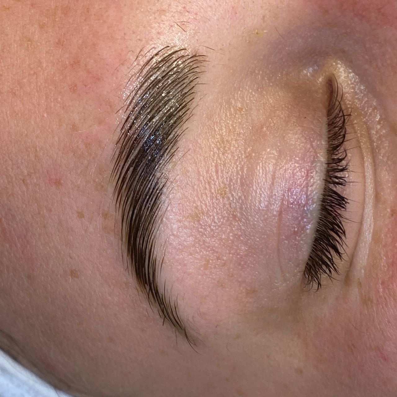 Close-up of a person's laminated eyebrow and closed eye.