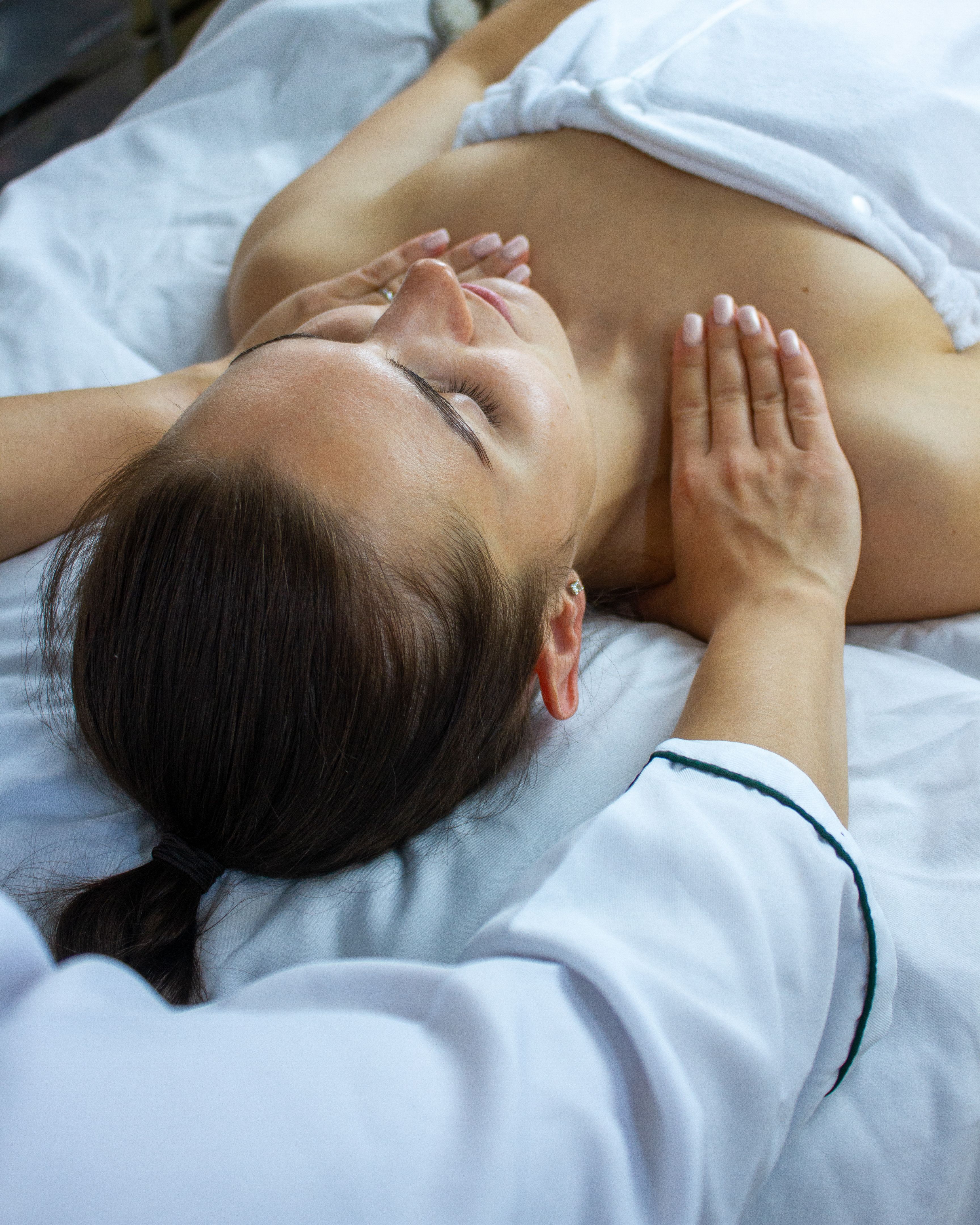 A woman with closed eyes receiving a chest and shoulder massage.