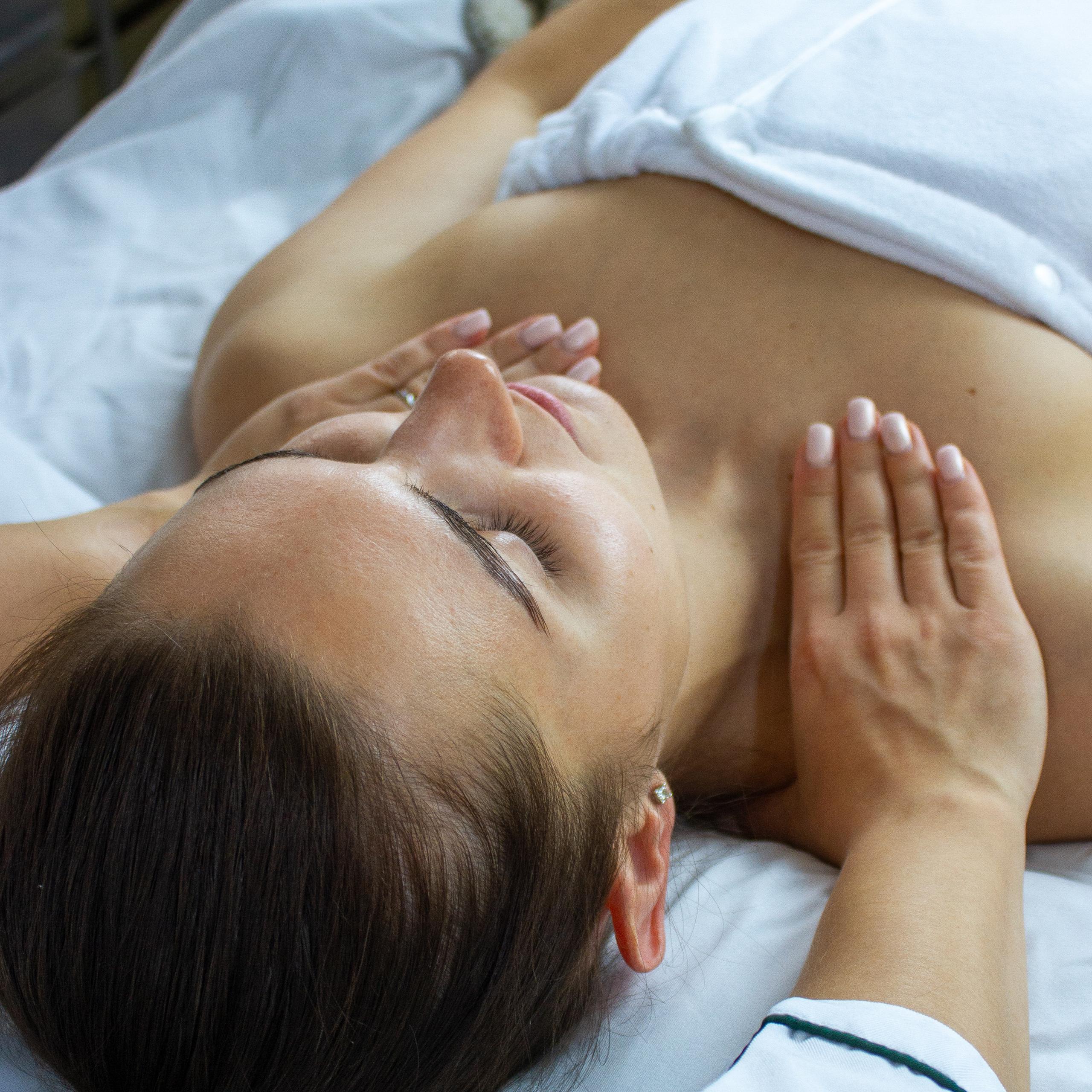 A woman with closed eyes receiving a chest and shoulder massage.
