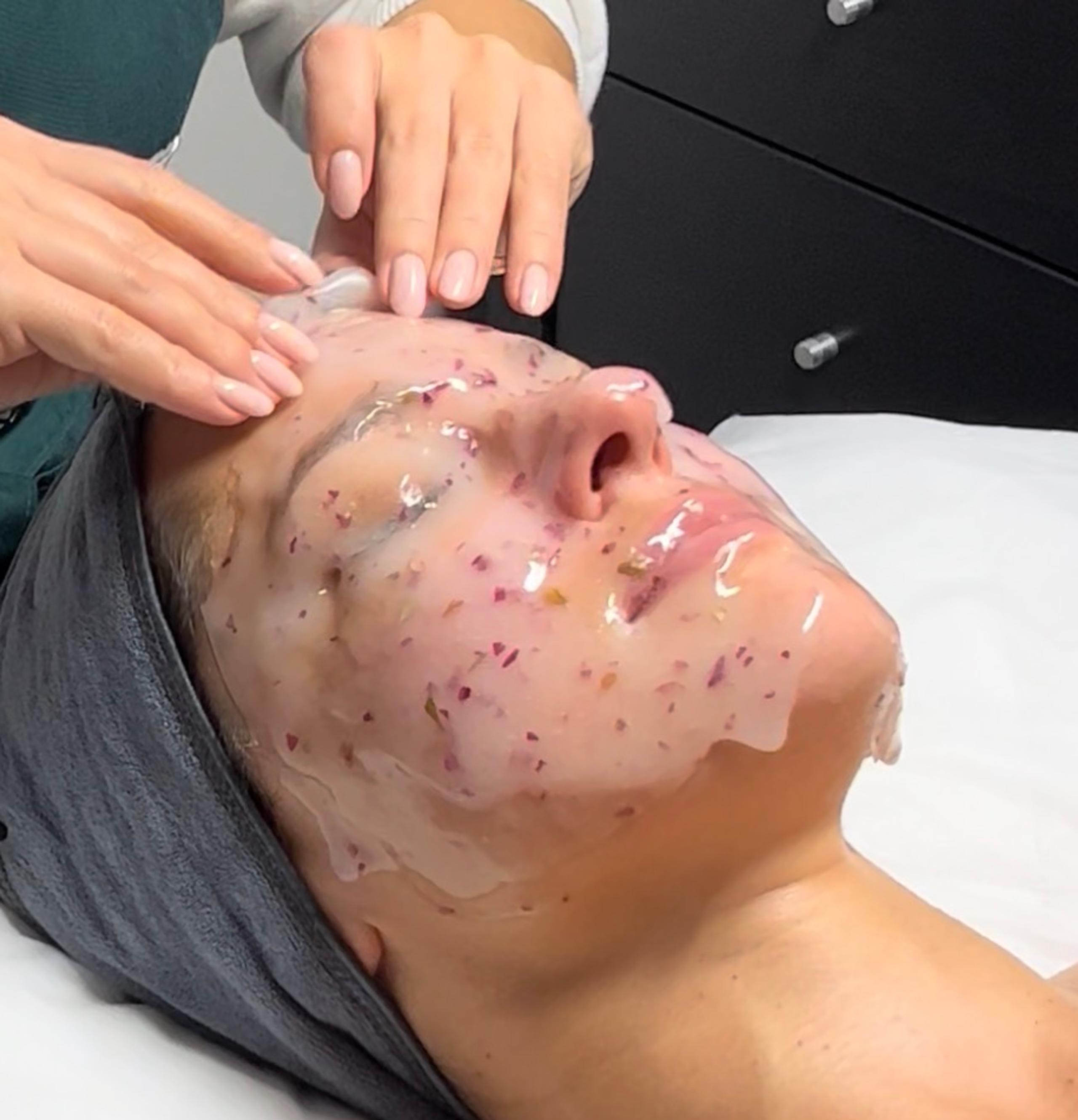 Esthetician is removing a rose hydrojelly mask from a woman's face