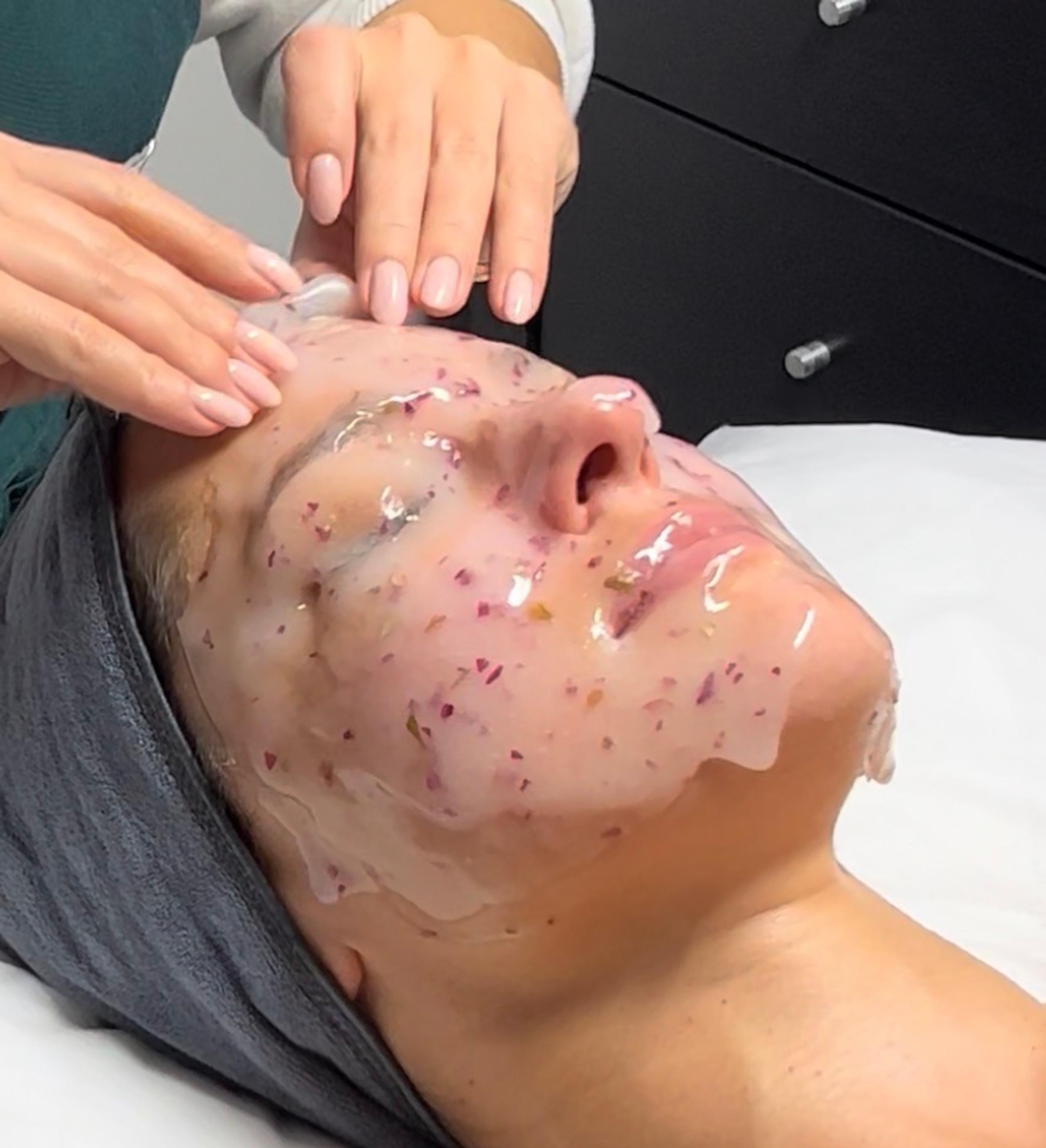 Esthetician is removing a rose hydrojelly mask from a woman's face