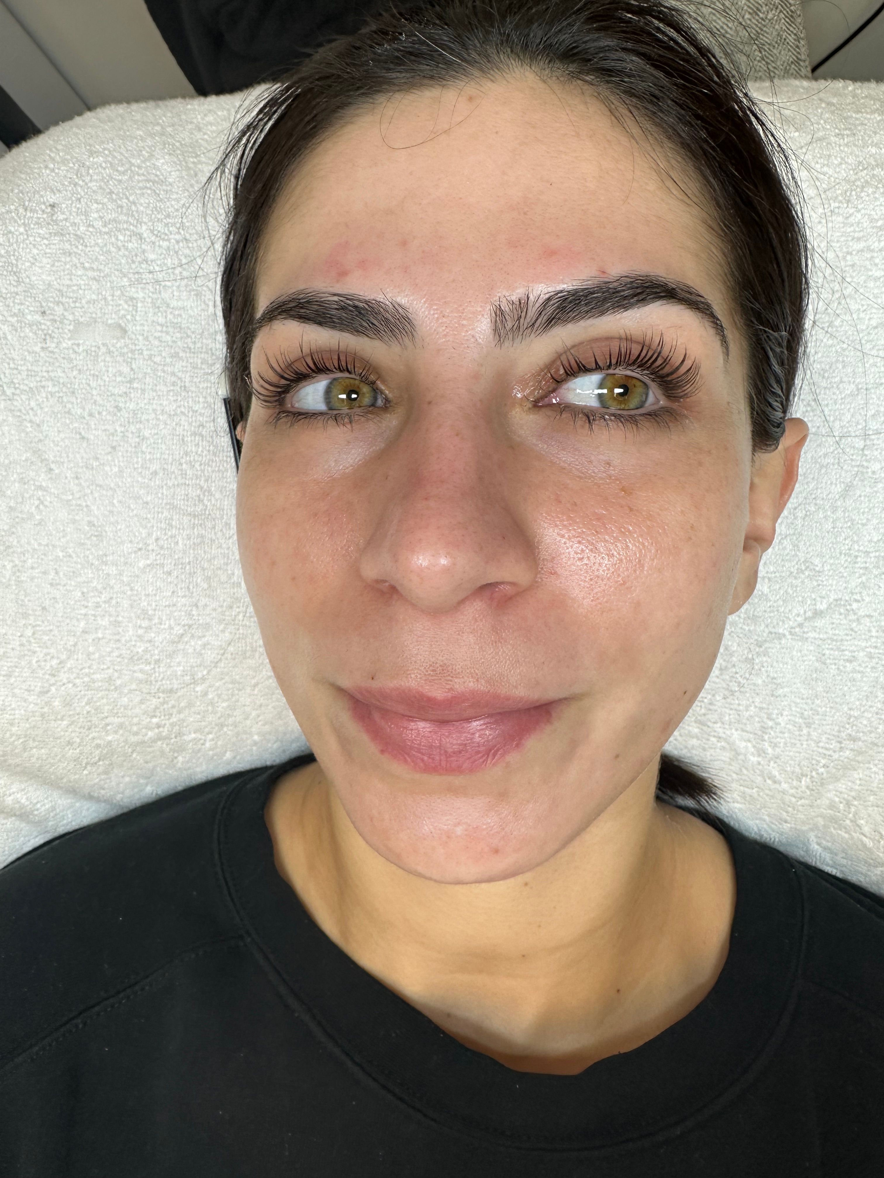 Close-up of a woman's face with long, curled eyelashes and green eyes looking to the side