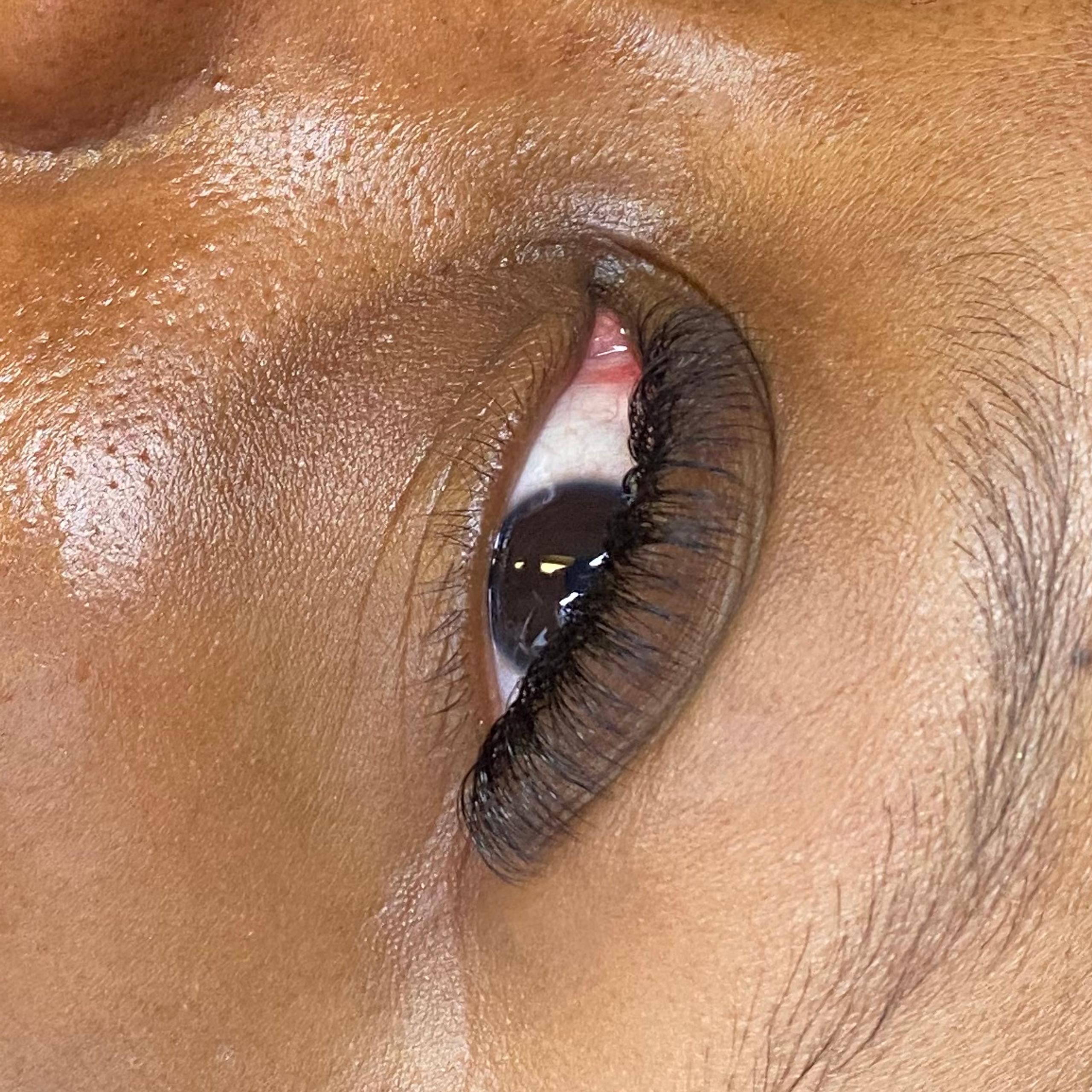 A person lying down, showcasing long eyelashes and dewy skin.