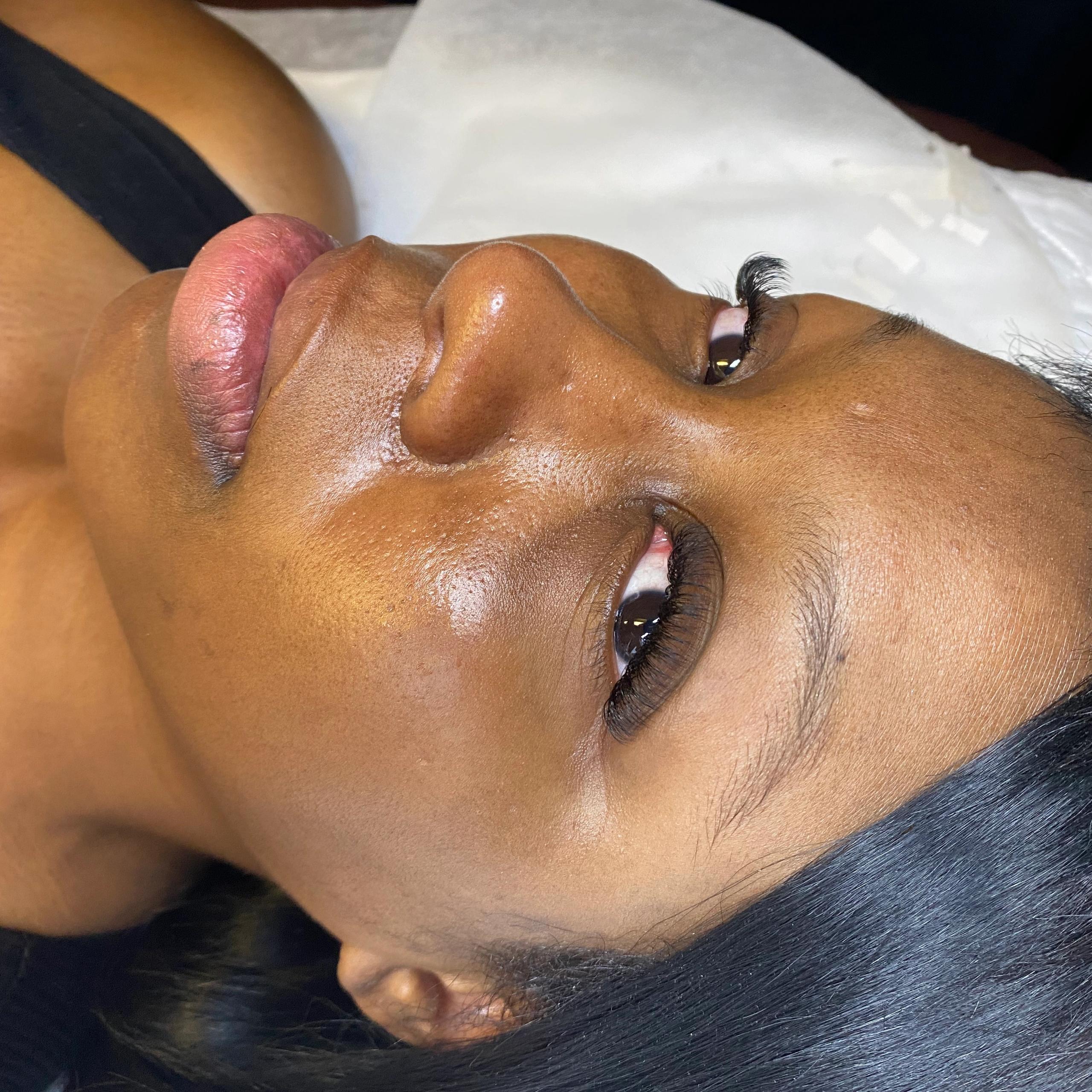 A person lying down, showcasing long eyelashes and dewy skin.