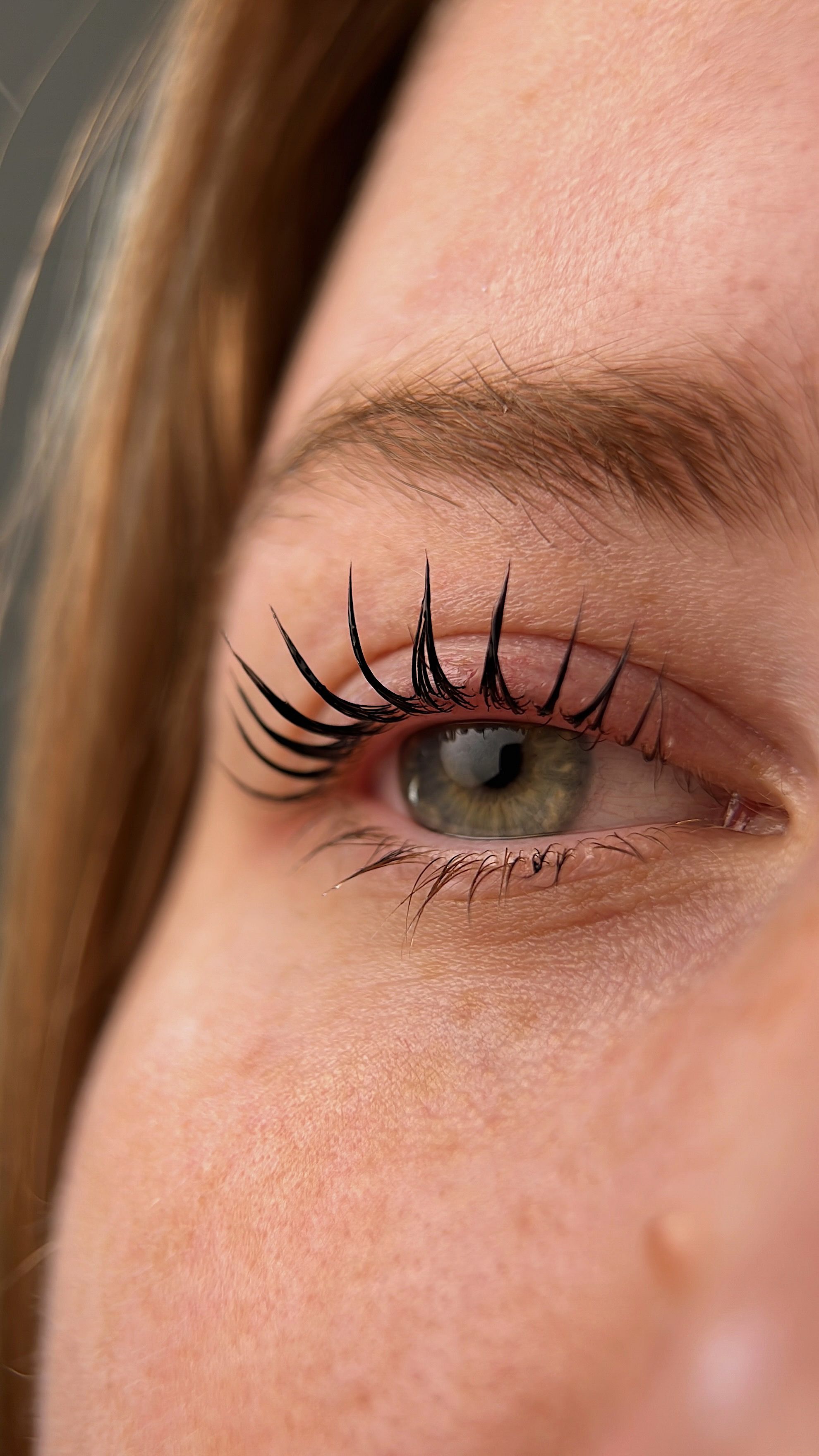 A woman with red hair and clear skin, showcasing lifted eyelashes