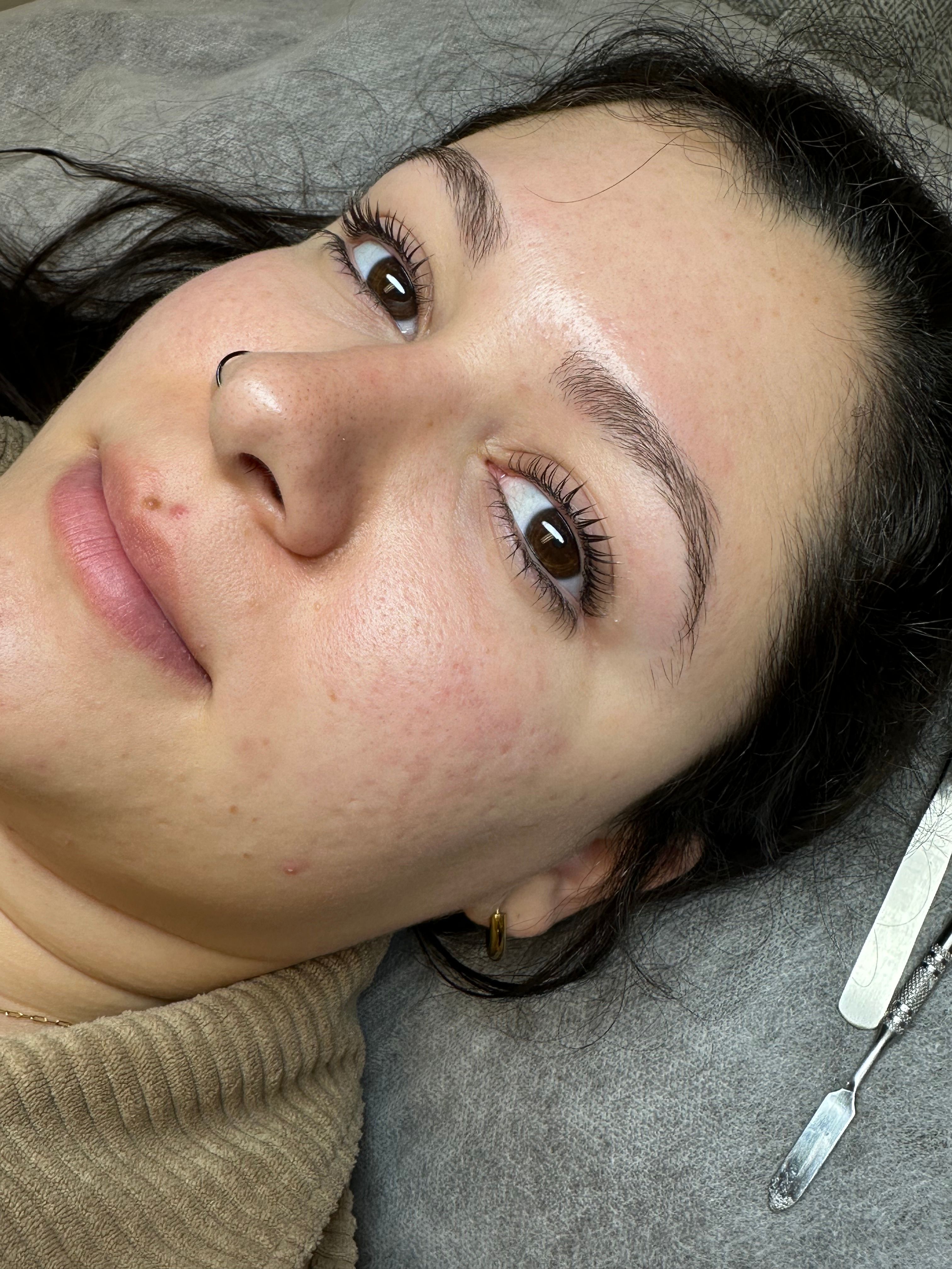Close-up of a woman's face highlighting curled eyelashes and well-groomed eyebrows.