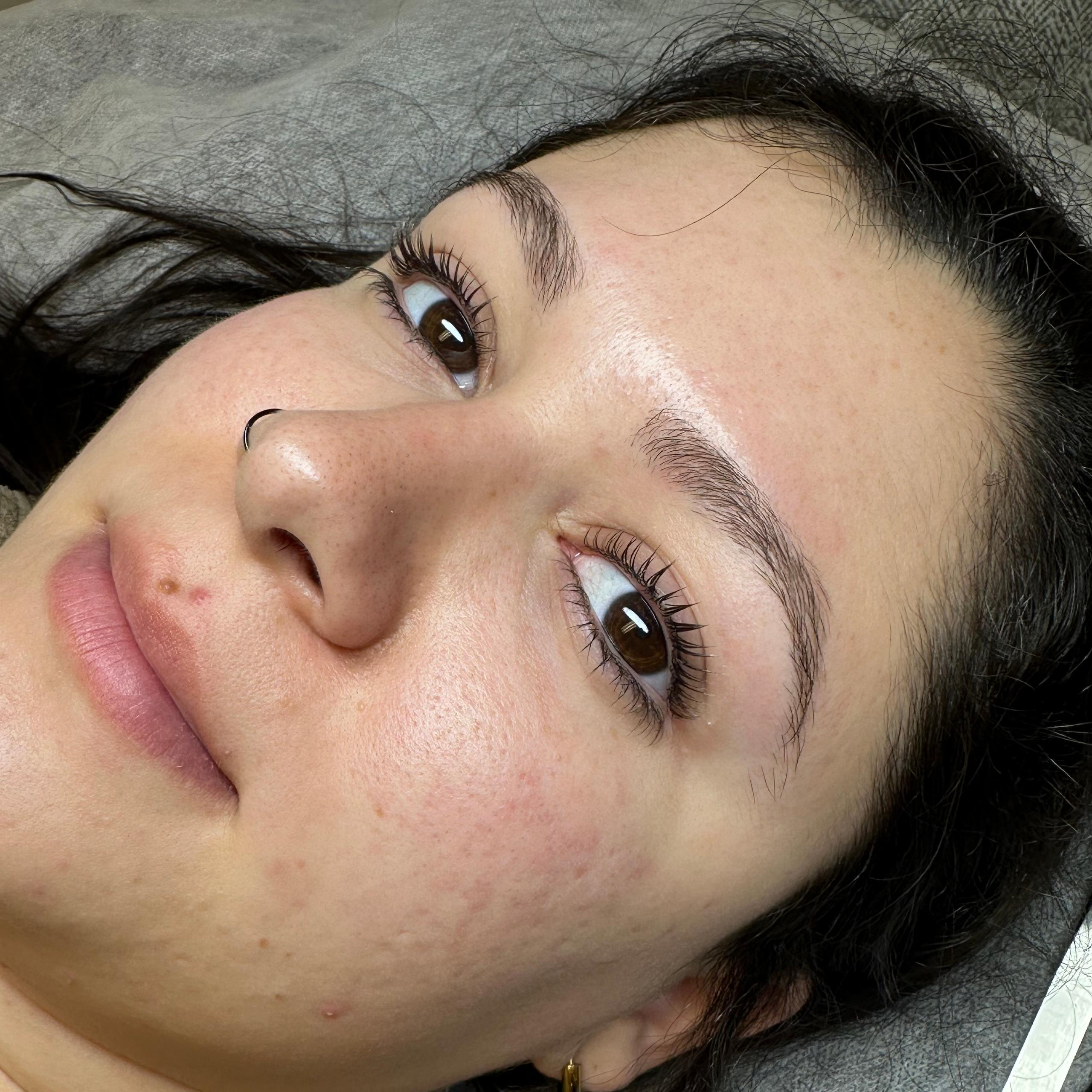 Close-up of a woman's face highlighting curled eyelashes and well-groomed eyebrows.