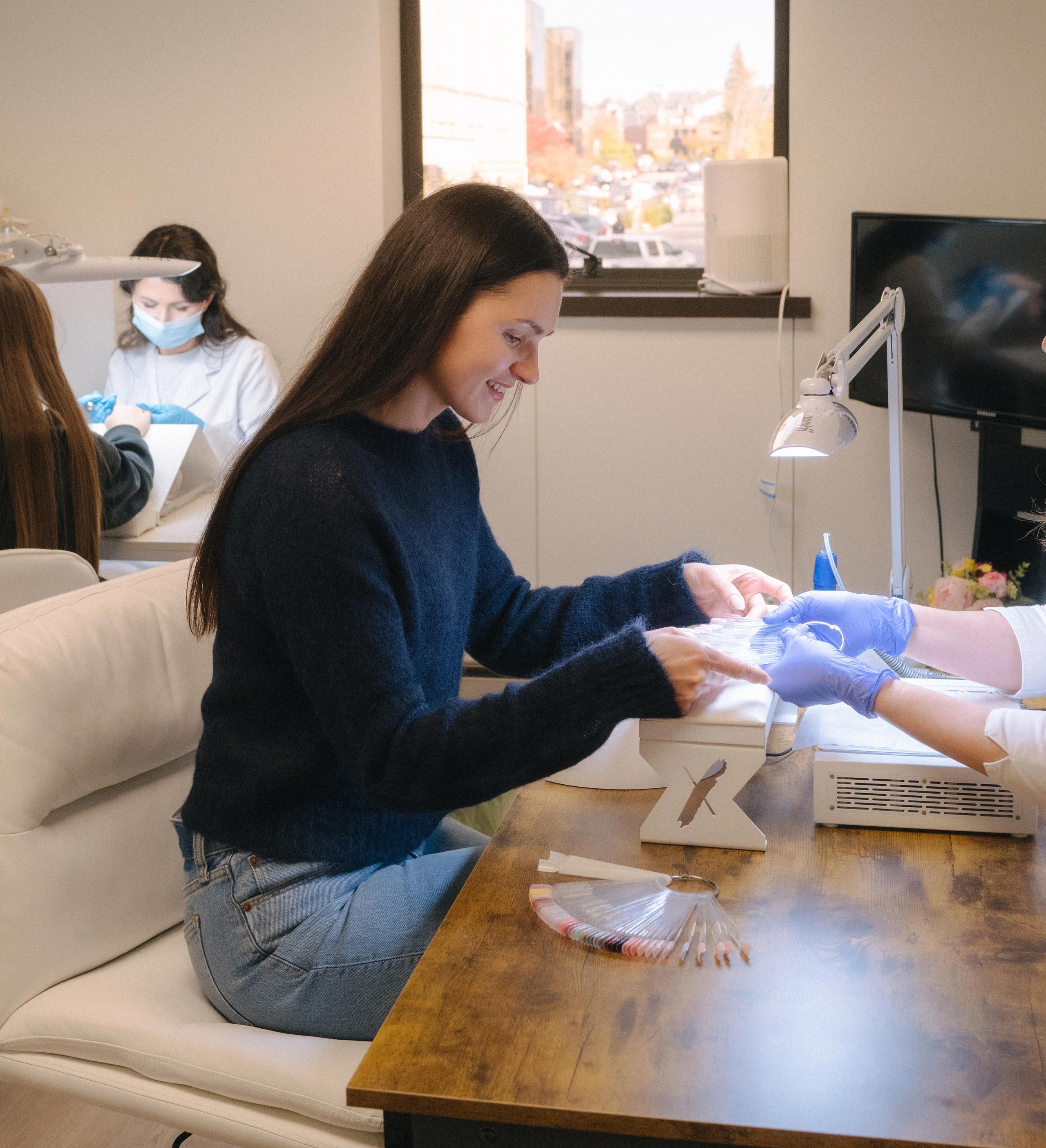 Two clients receiving a manicure at salon tables