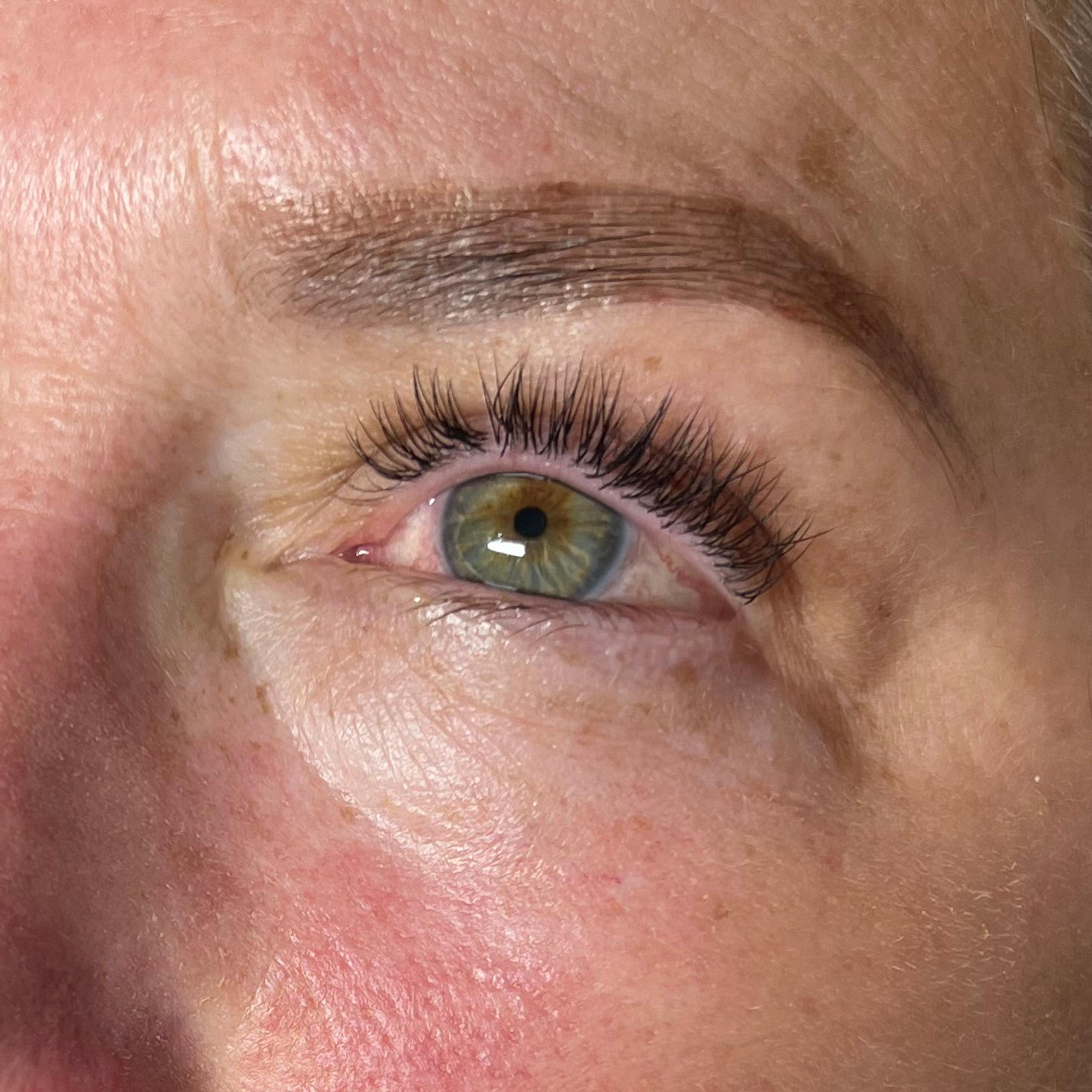 A woman's face showing dark, full eyelashes and brown tinted brows