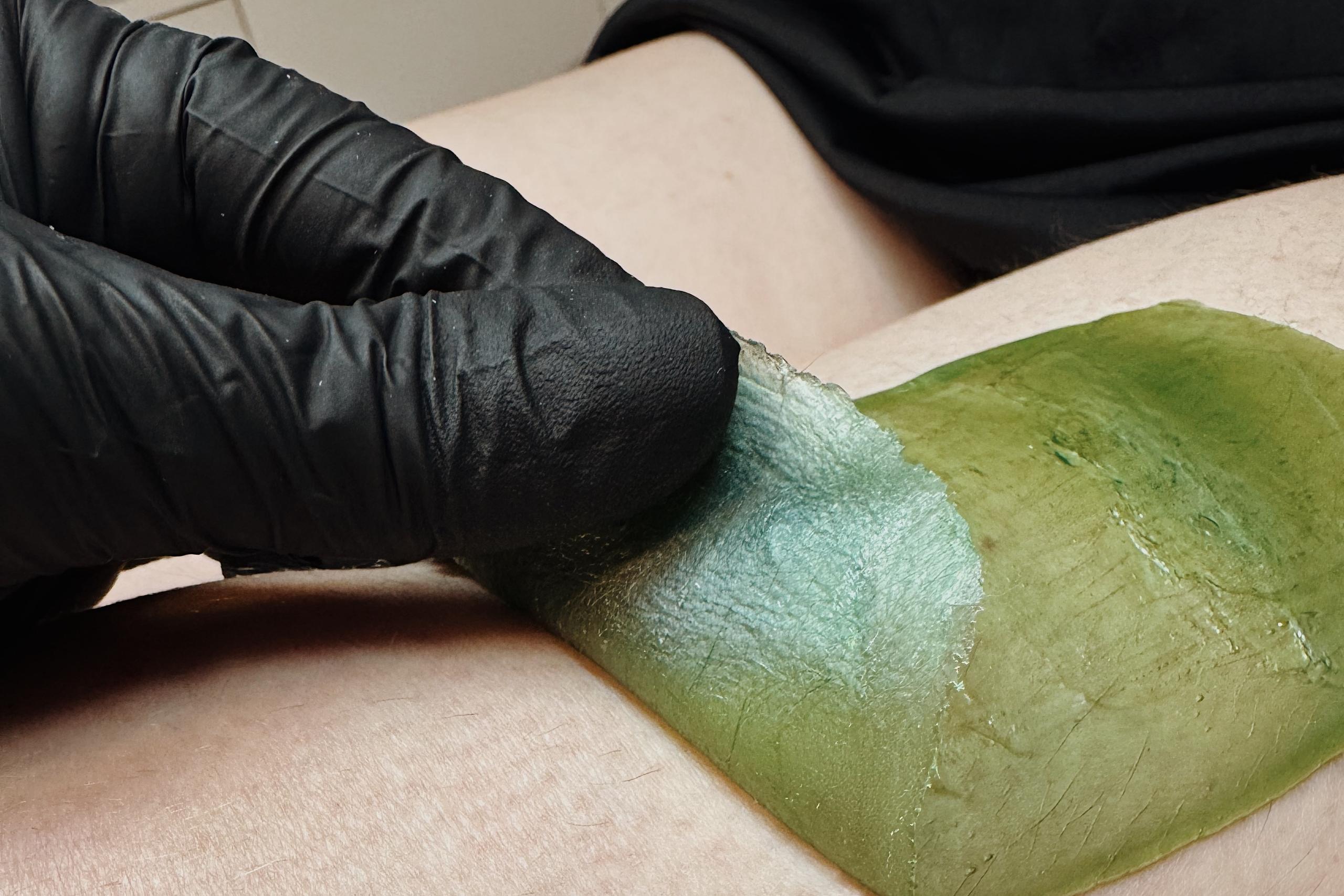 A cosmetologist waxes a girl's eyebrows