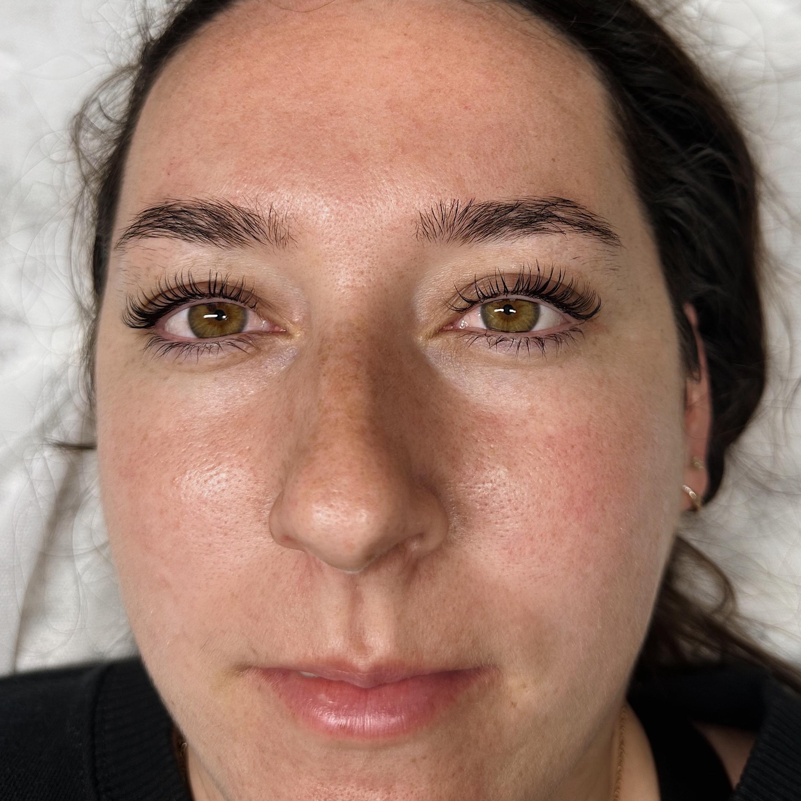 Close-up of a woman's face highlighting curled eyelashes and well-groomed eyebrows.